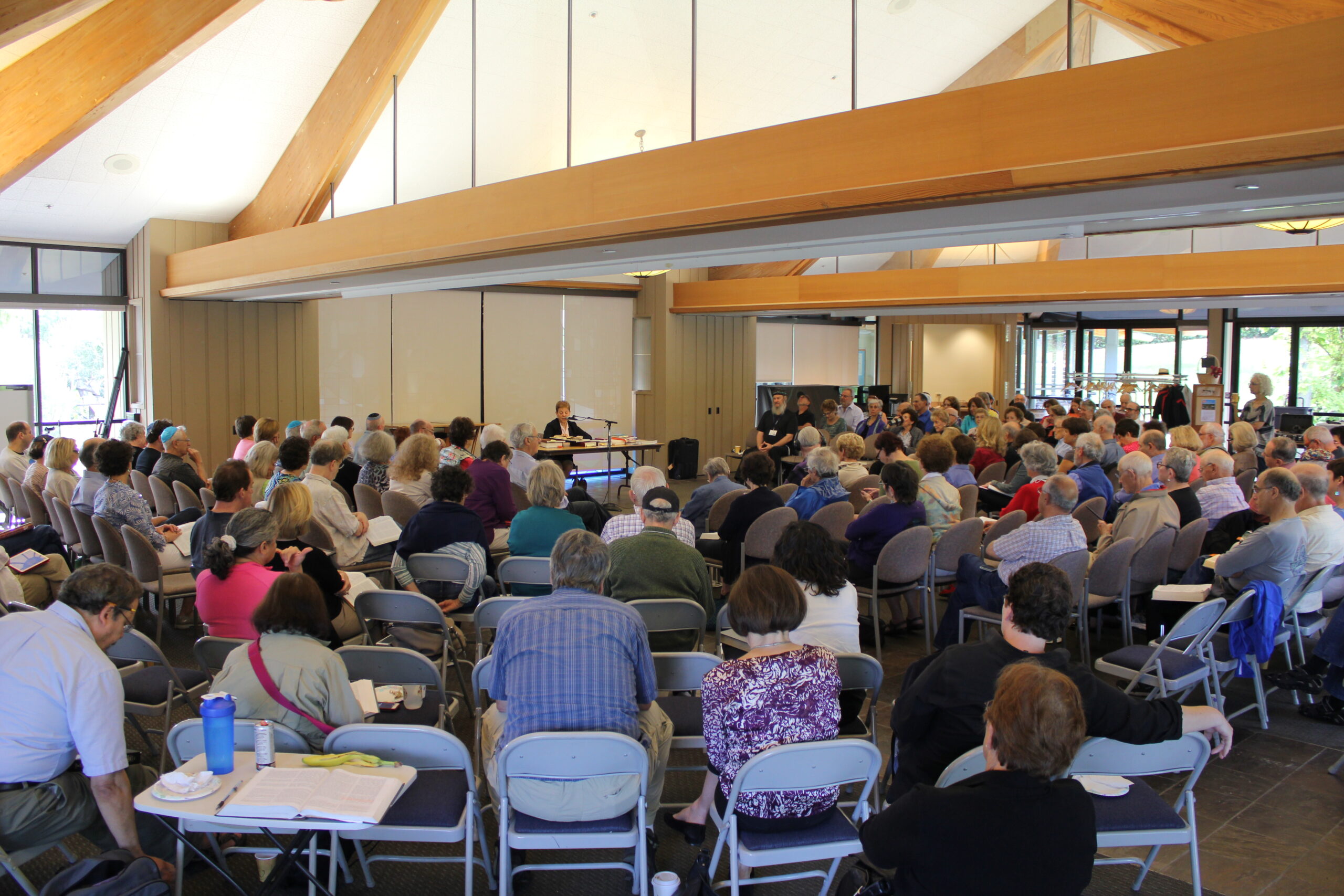 marder sits at a table in front of concentric half circles of a very large number of people