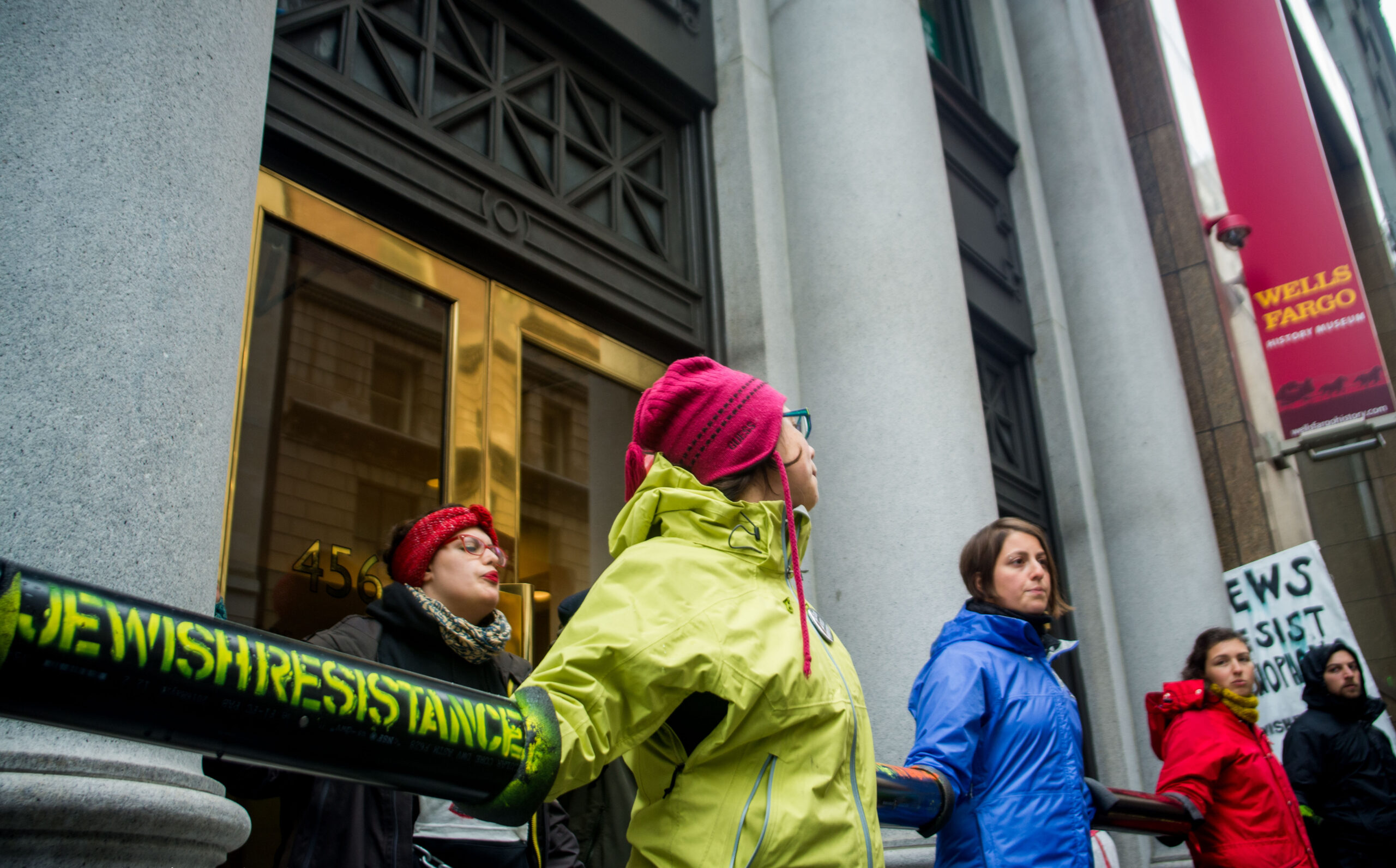 Protesters have their arms linked in long black tubes to block the entrance to the building