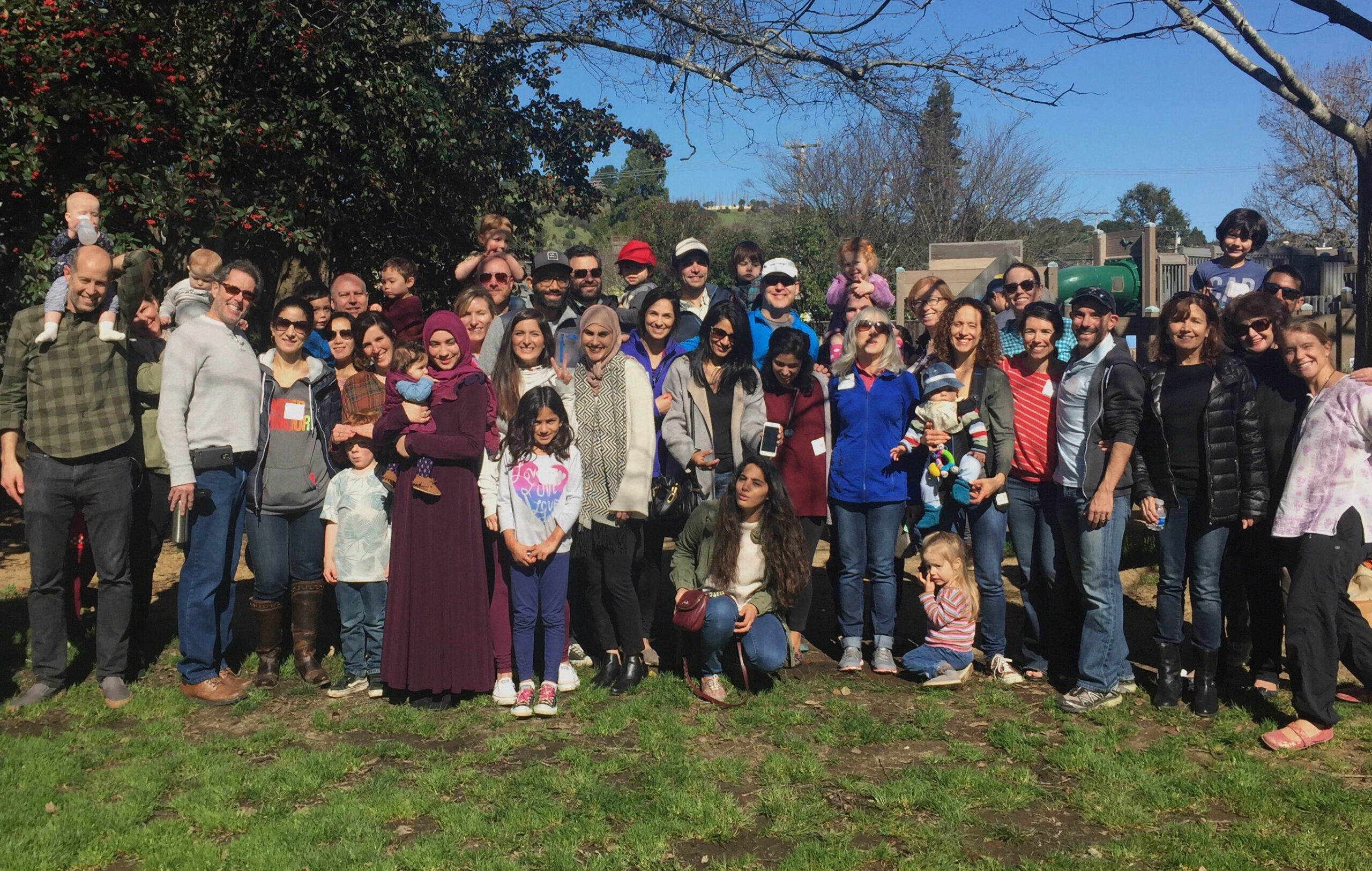A big group portrait of many people, including some women in hijabs
