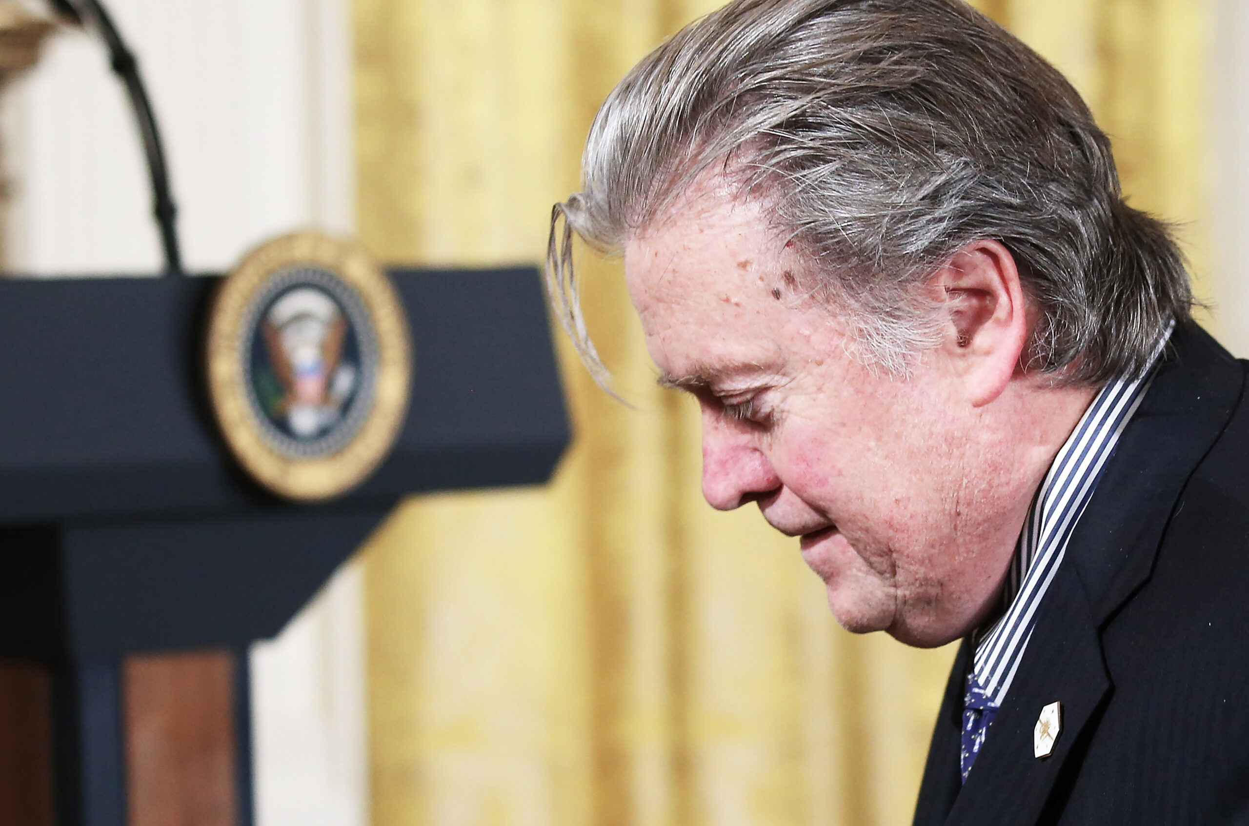 Bannon in profile, with POTUS podium behind him