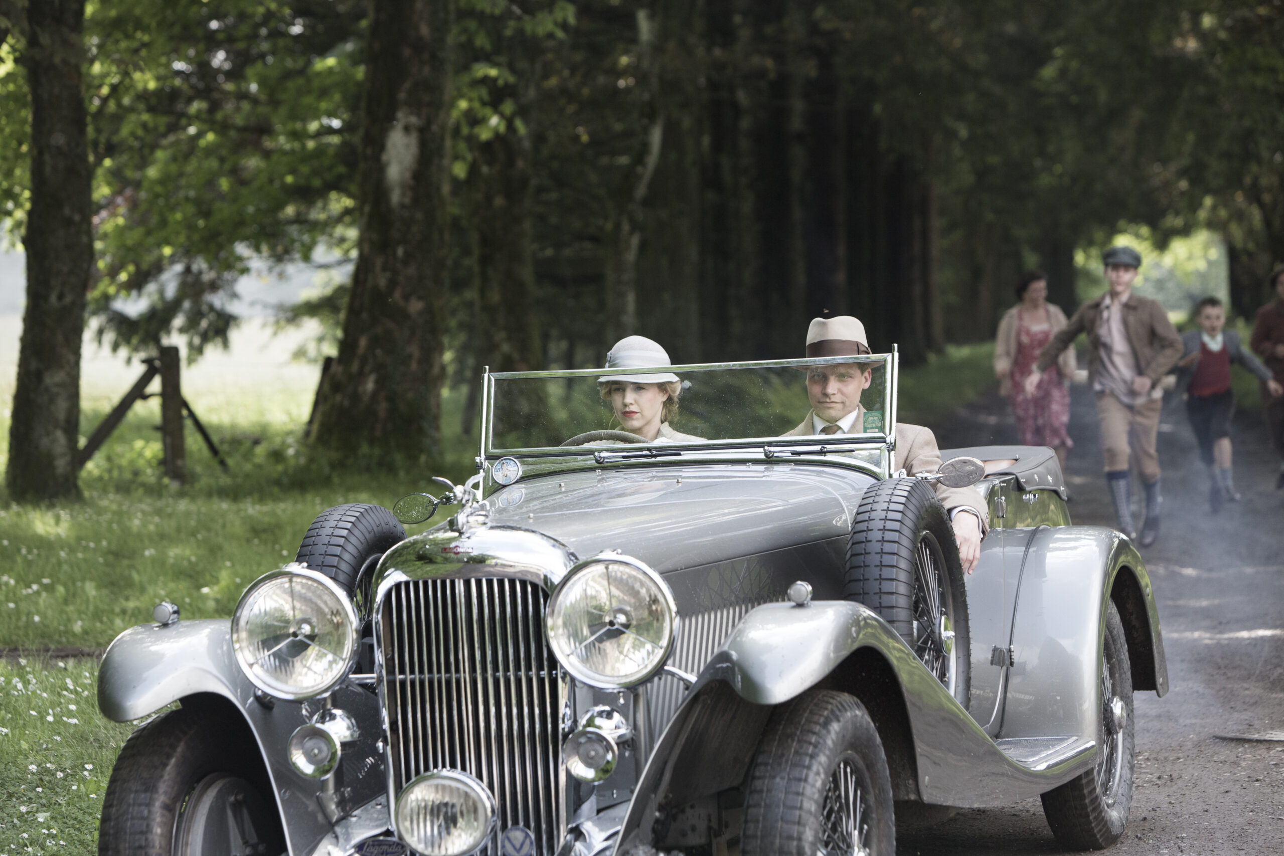 Two people in a 30s-style car