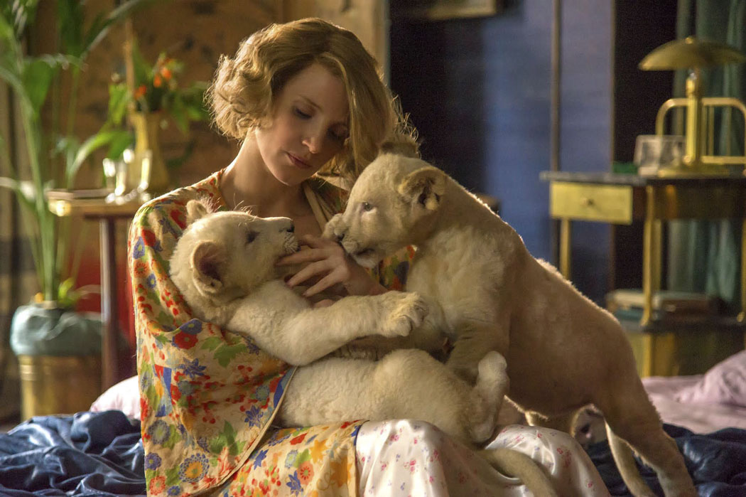 chastain sits cradling two lion cubs