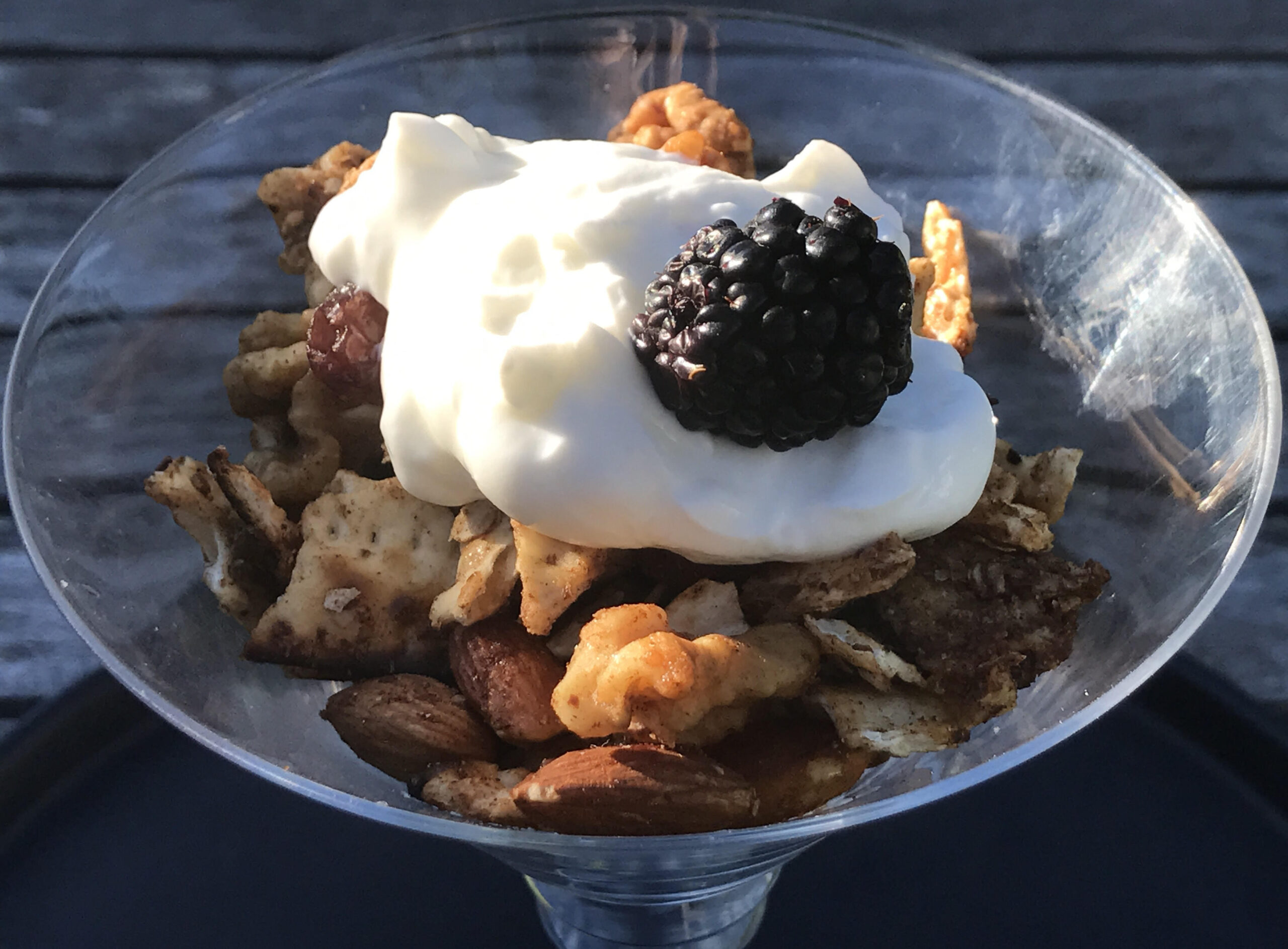 glass dish filled with matzolah and cream, topped with a blackberry