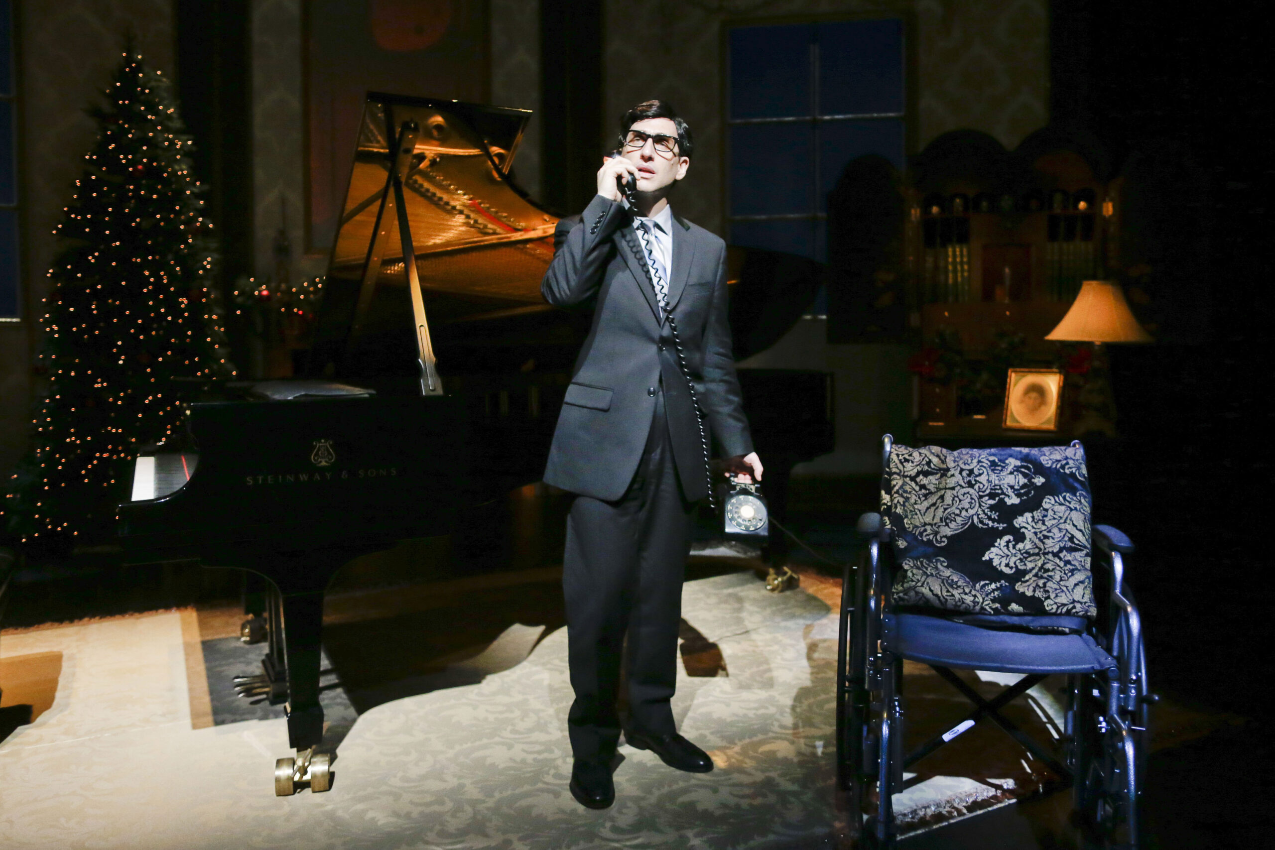 felder stands on stage speaking on a prop rotary phone