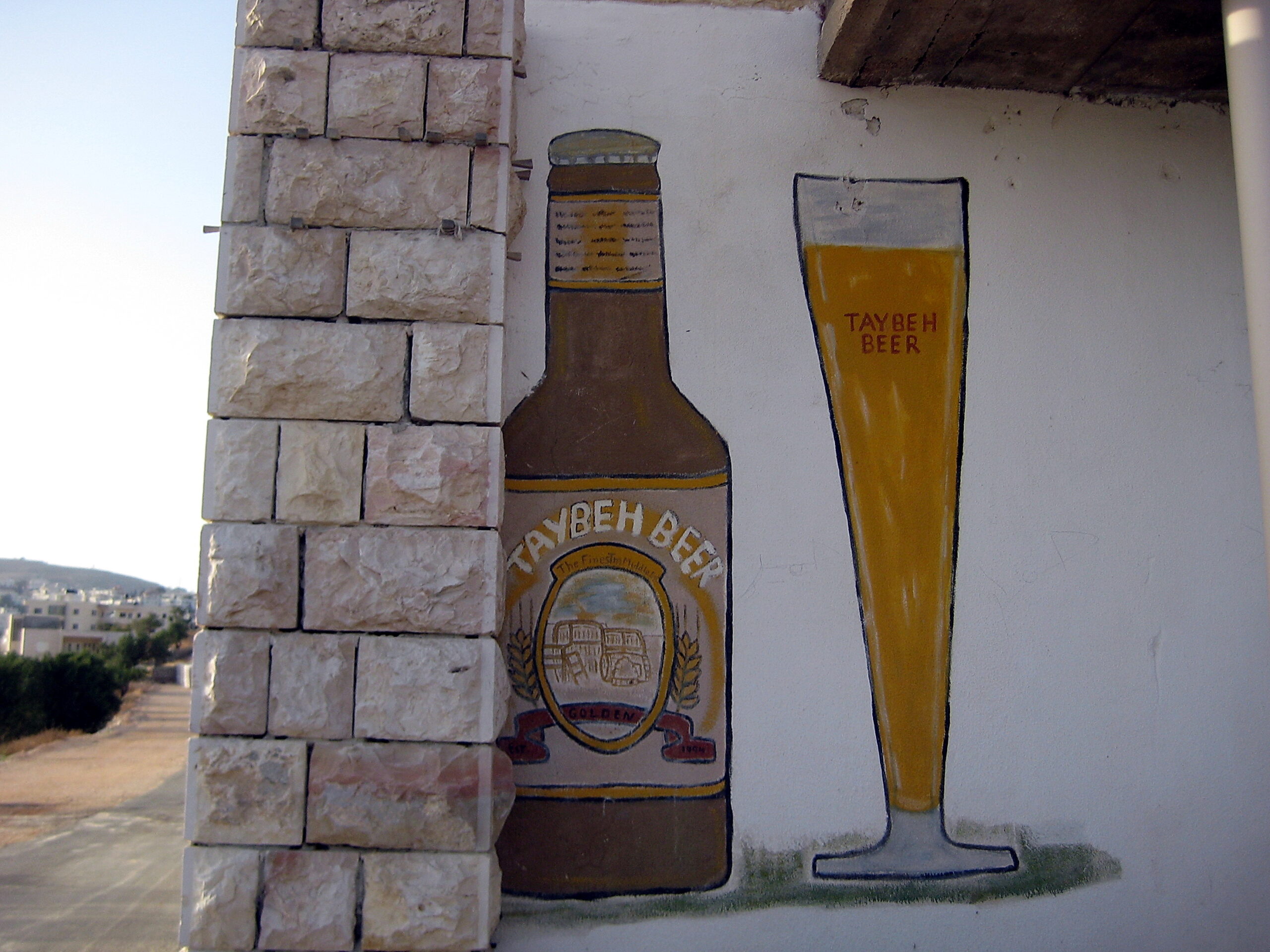 a painting of a bottle of Taybeh beer on a wall