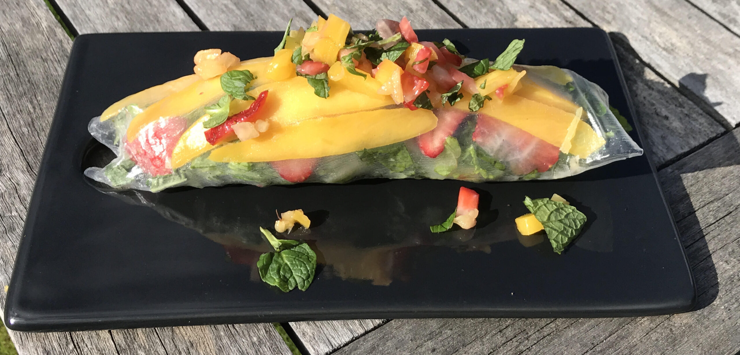 brightly colored roll of food on a black plate