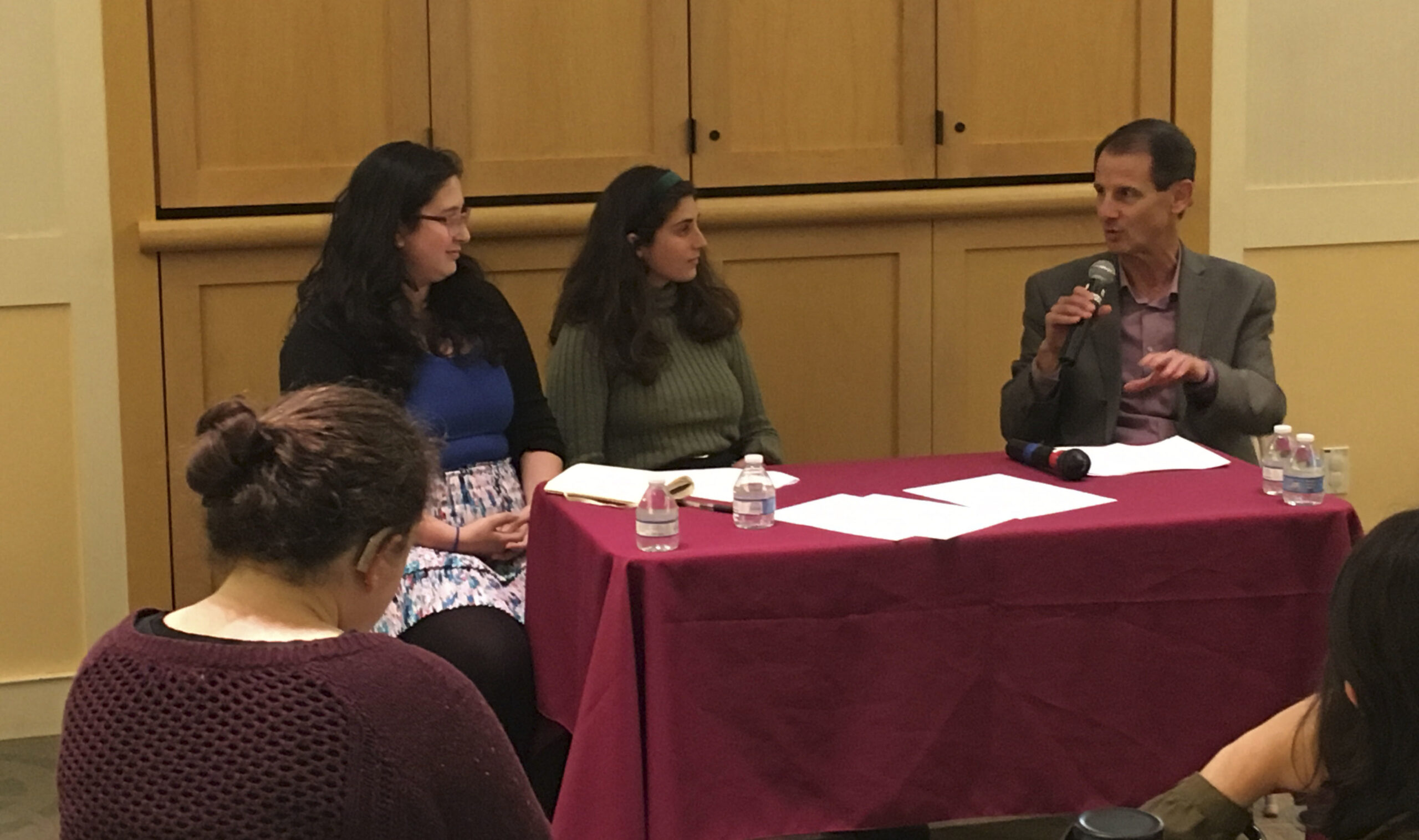 the two women sit at a table with grossman, who is speaking into a microphone