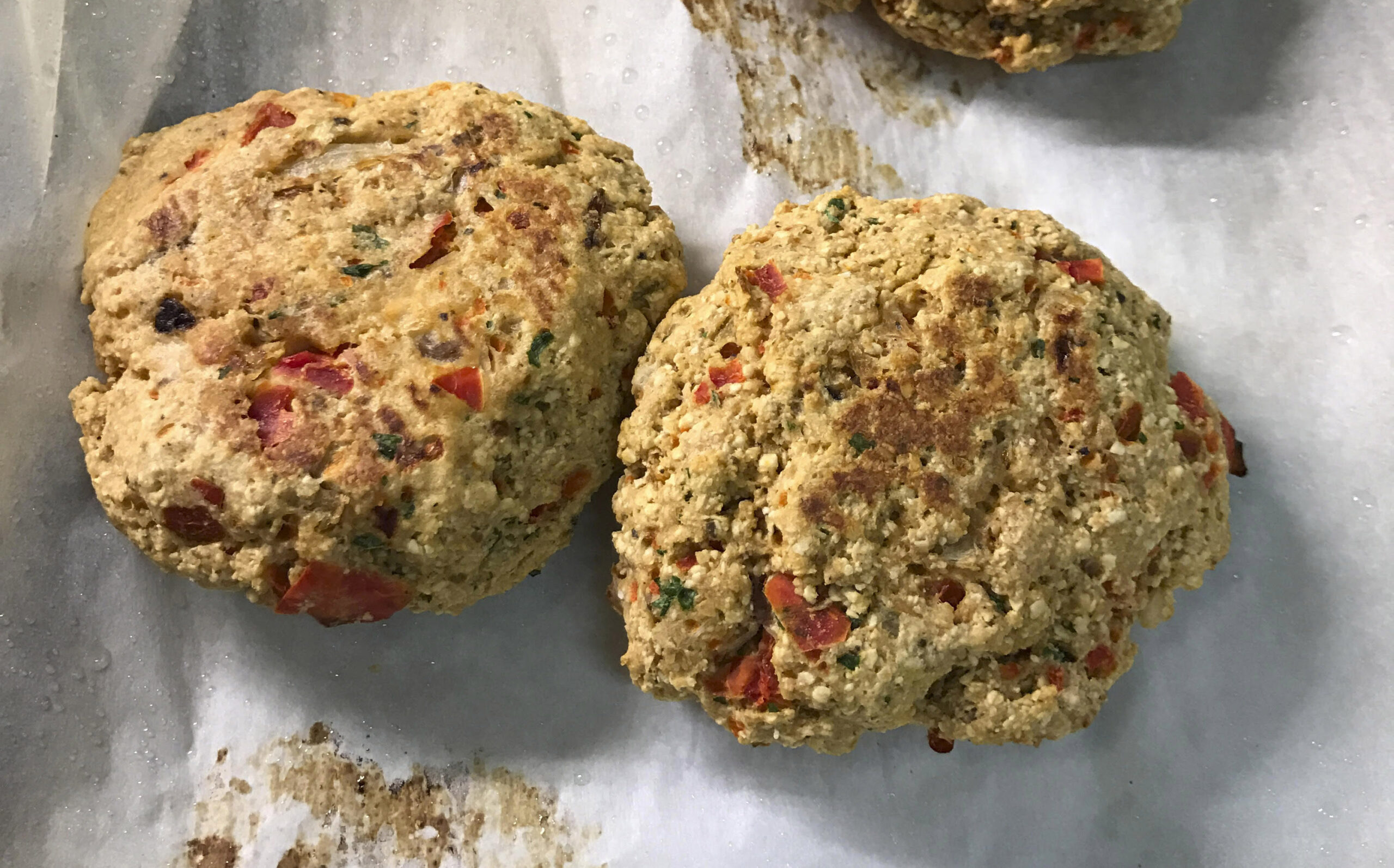 two golden salmon croquettes sit on a baking sheet
