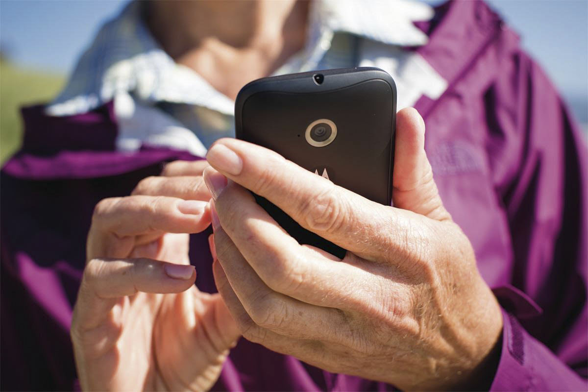 an older woman holds a cell phone