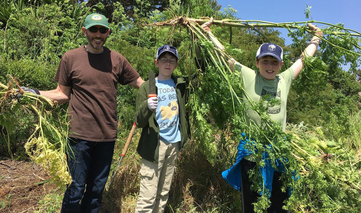 a man and two boys pose while doing yardwork