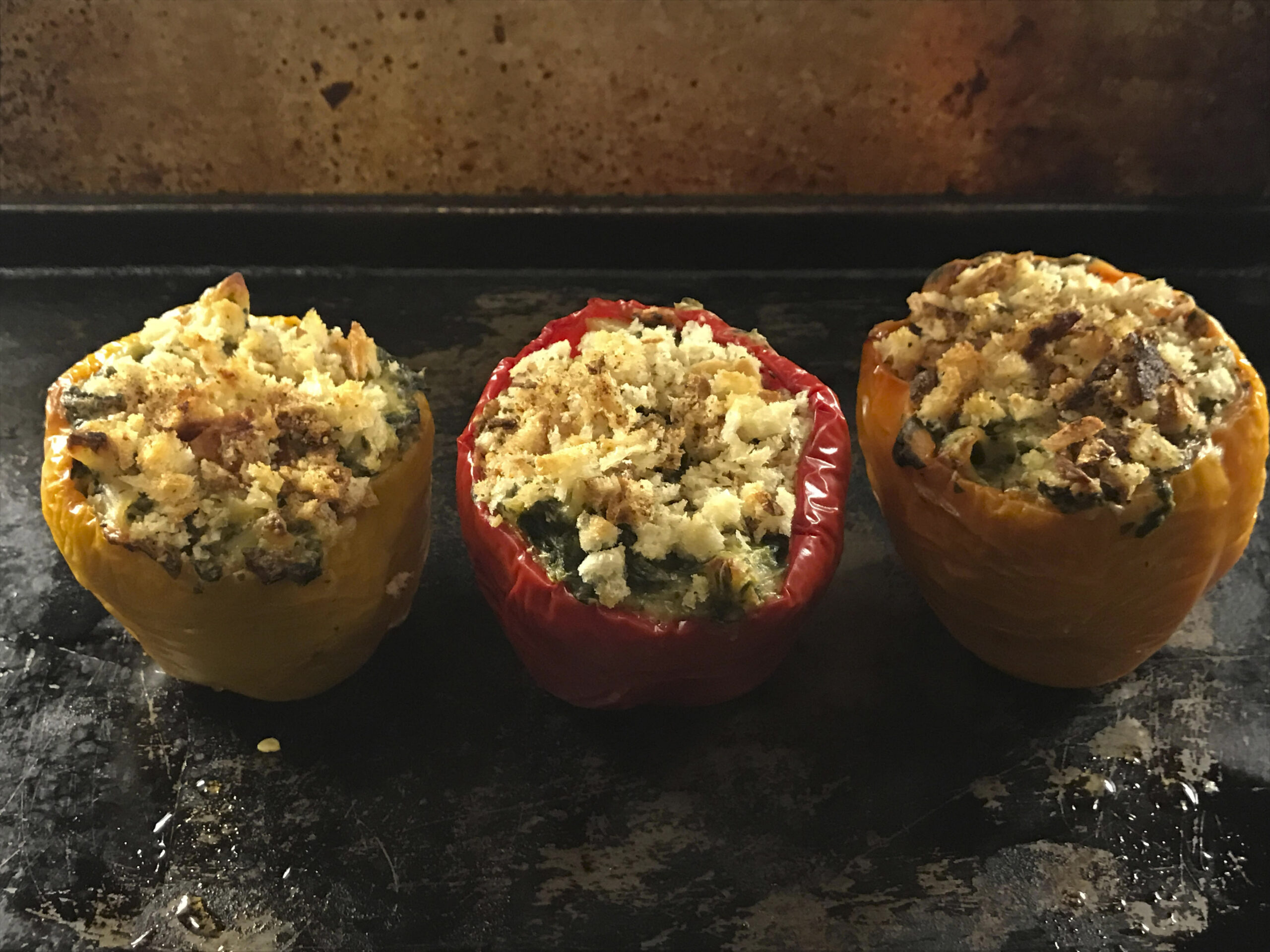 three bell peppers (two red, one yellow), stuffed with mac and cheese