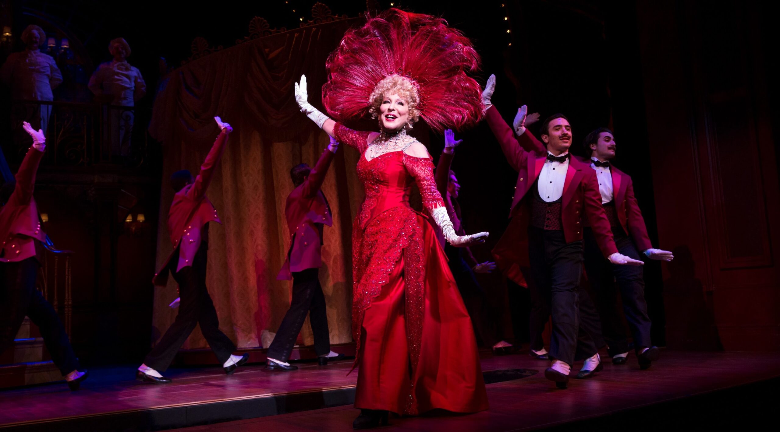 midler dancing in an elaborate red dress and feathered headwear