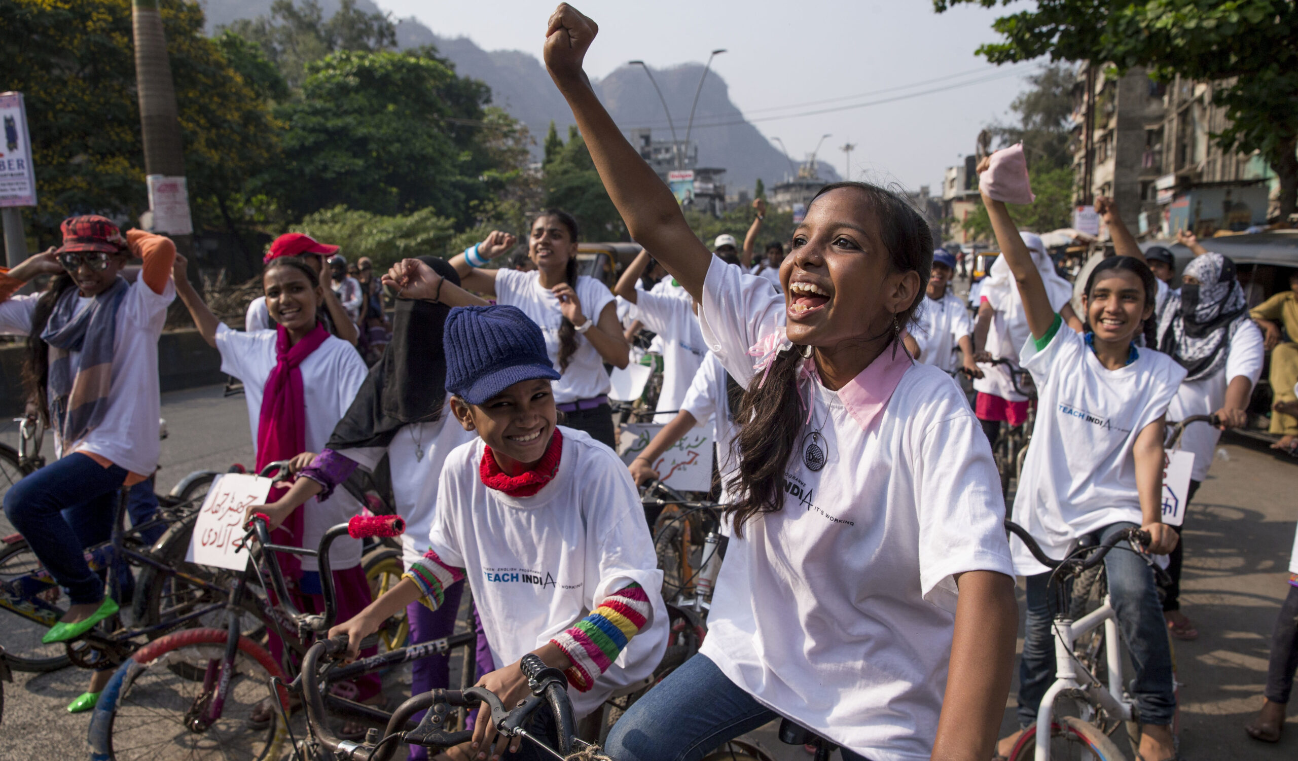 a bunch of young women on bicycles cheer and pump their fists in the air