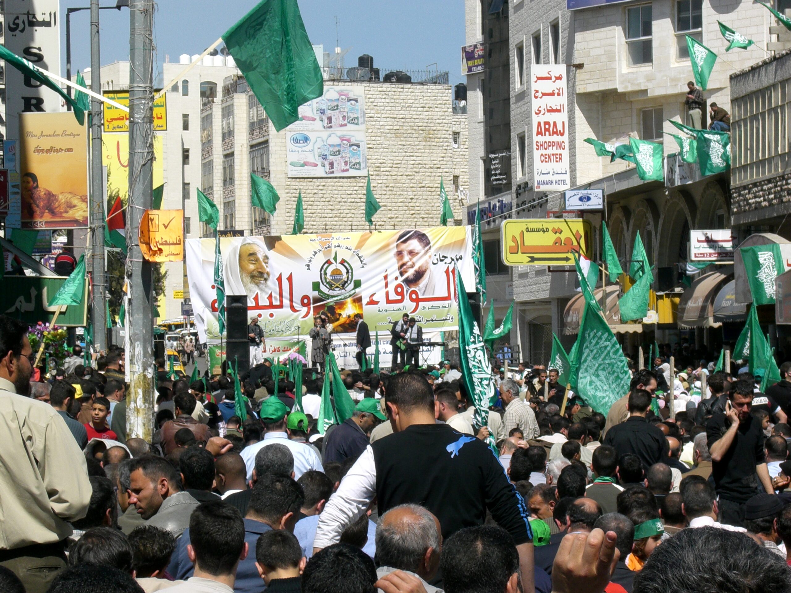a rally fills a square with people and green hamas flags