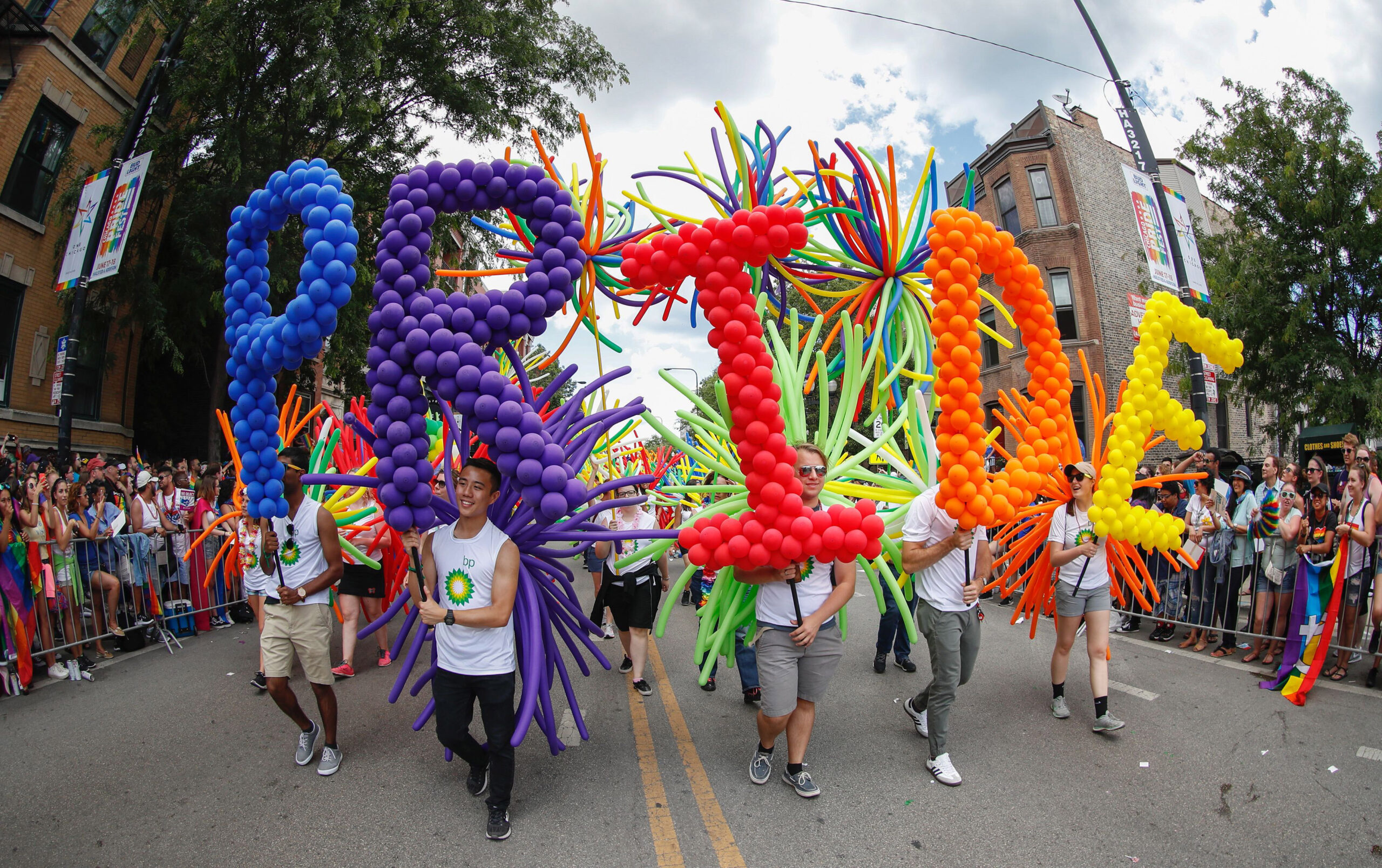 marchers carry extravagant balloon sculptures that spell out "PRIDE"