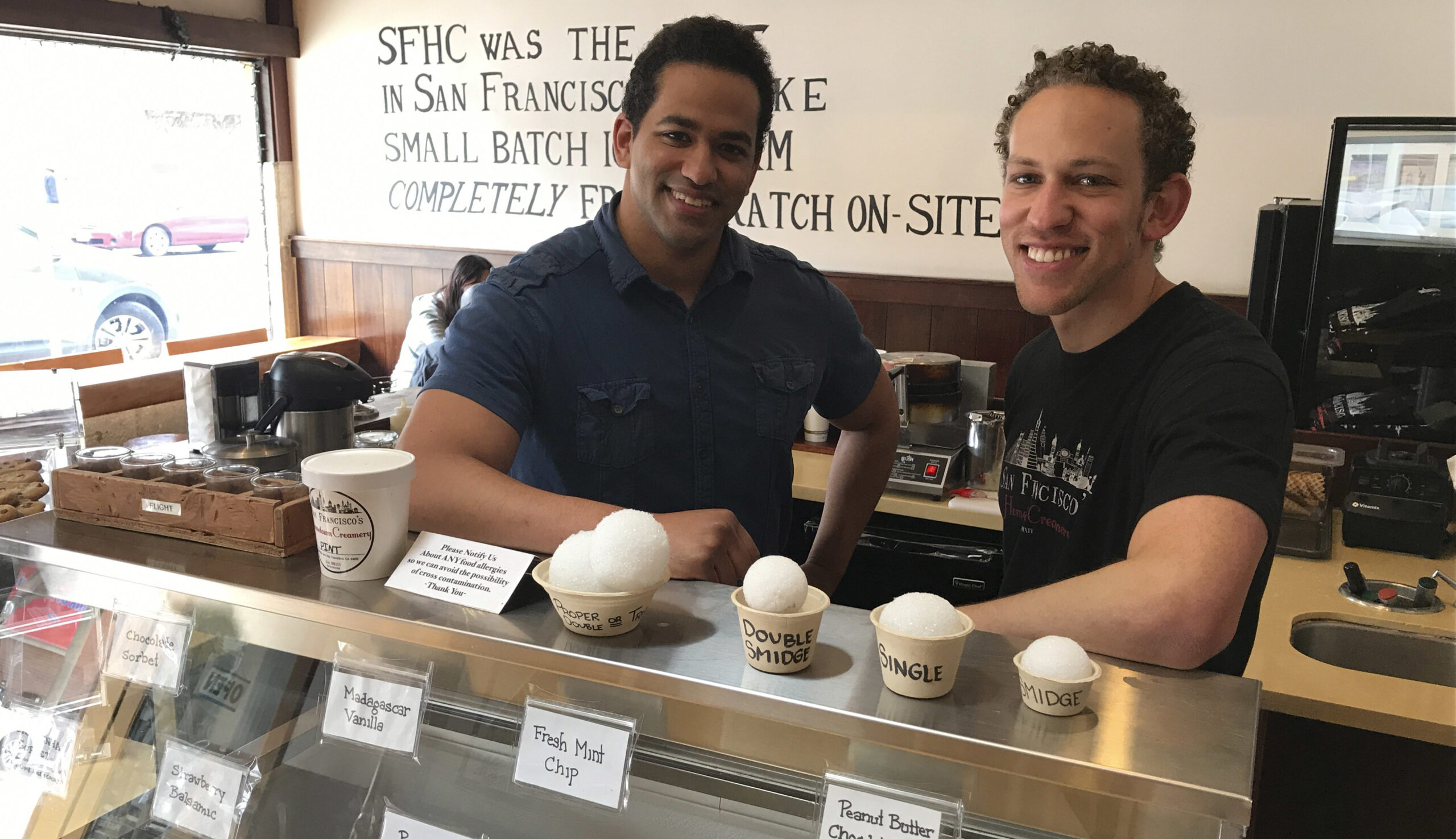 they stand behind an ice cream display case