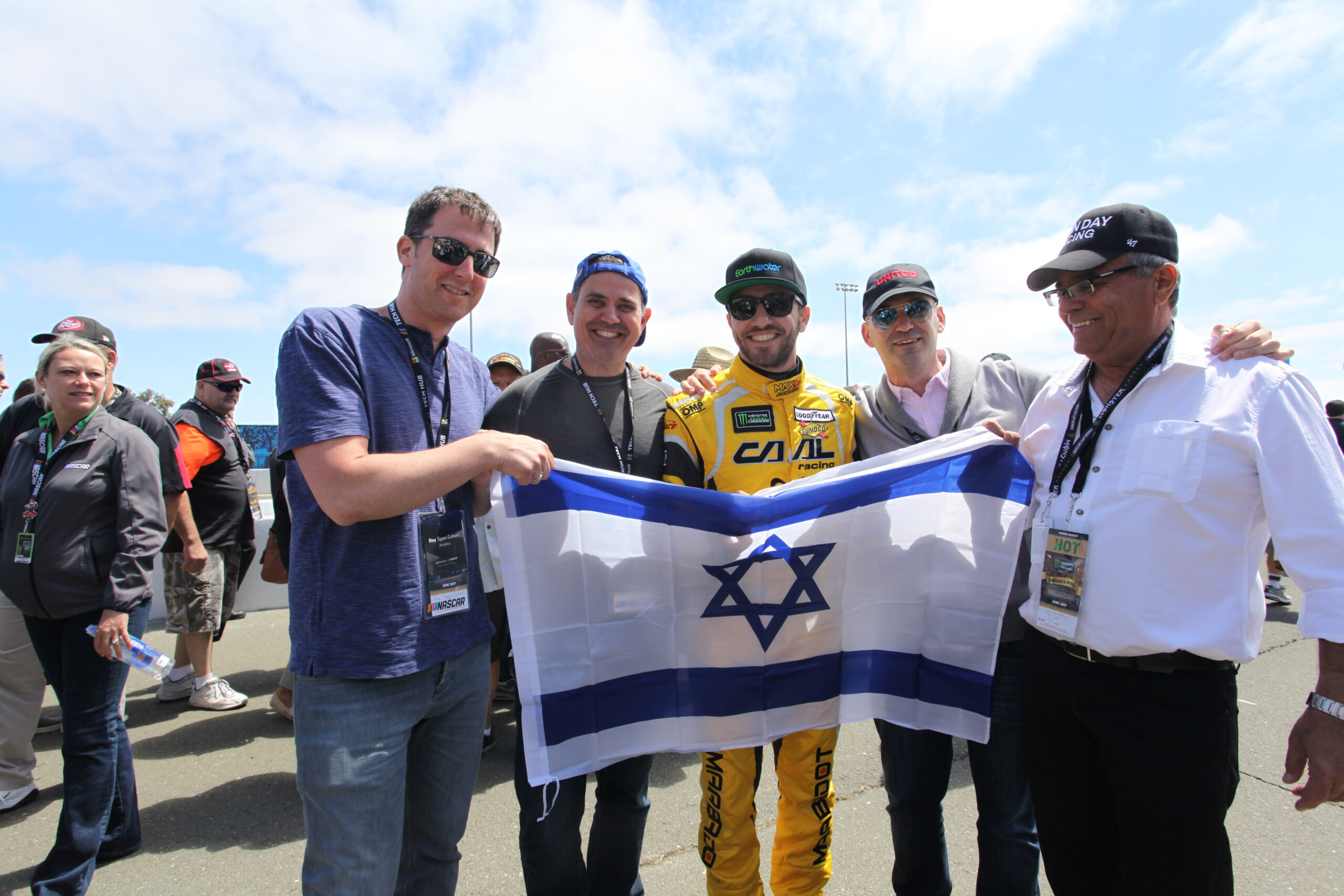 Israeli NASCAR driver Alon Day (center) with (from left) Roy Cohen, Avishai Sharlin, Dan Hod and Avi Day (Alon’s dad) at the Sonoma Raceway unfurling an Israeli flag (Photo/Max A. Cherney)