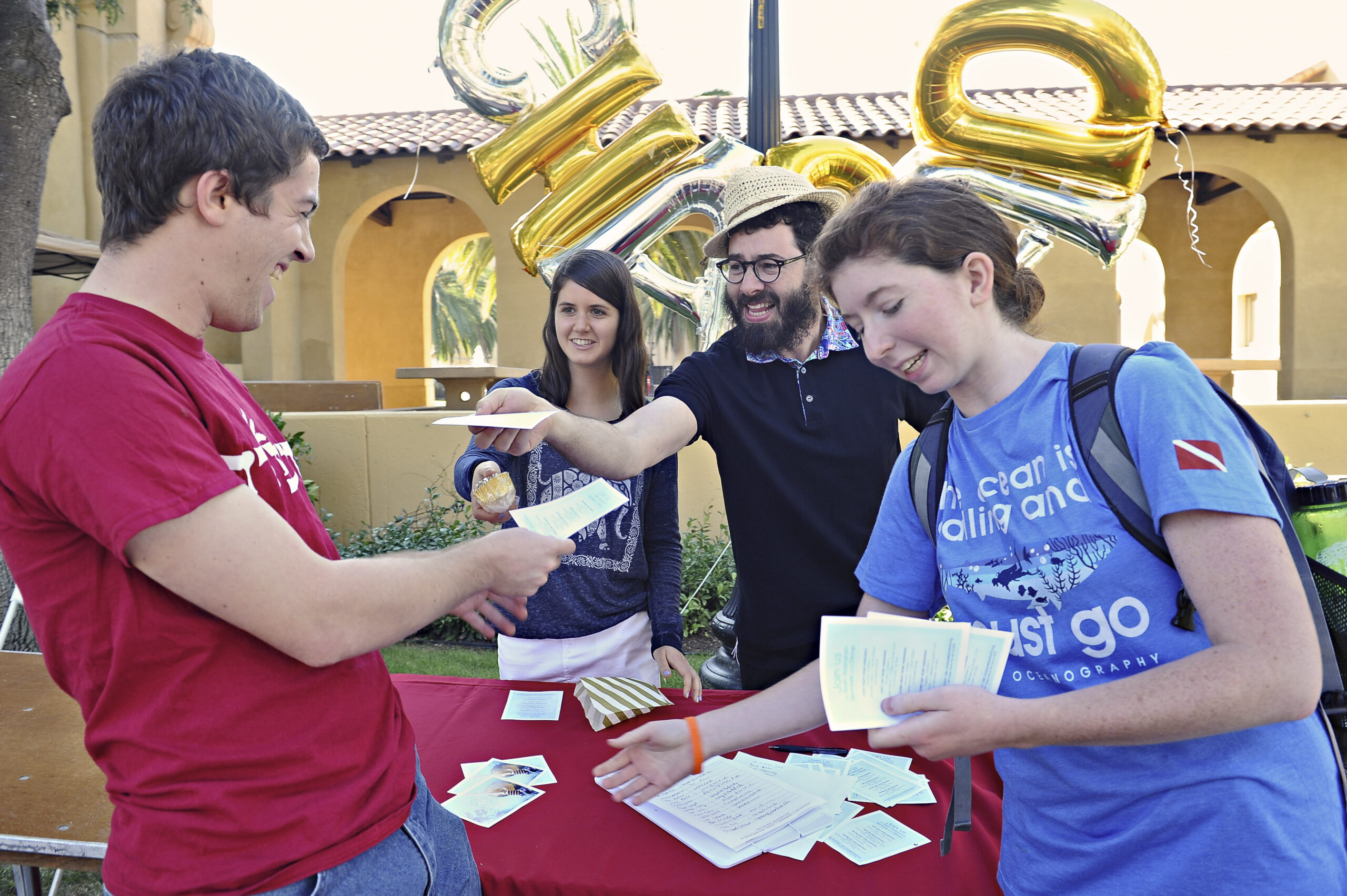 Outside Stanford’s Chabad Building, Rabbi Dov Greenberg and assistant Goldie Shaw (behind the table) talk with students Jonas Shomorony and Madeline Lee in September 2016. (Photo/Joyce Goldschmid)