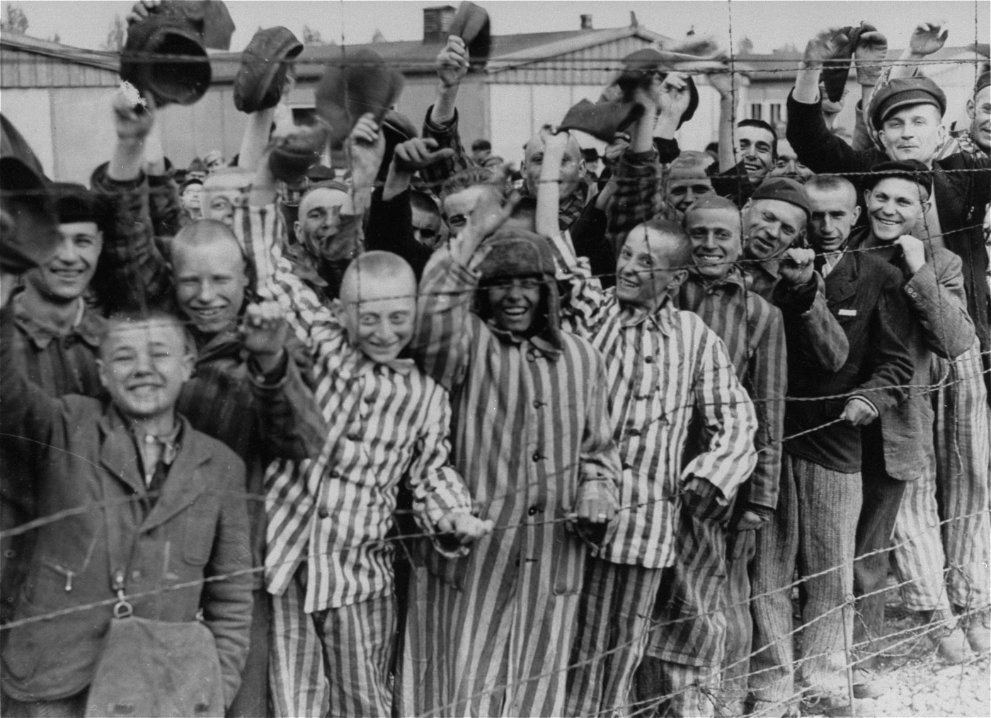 Young and old survivors in Dachau cheer approaching U.S. troops.
