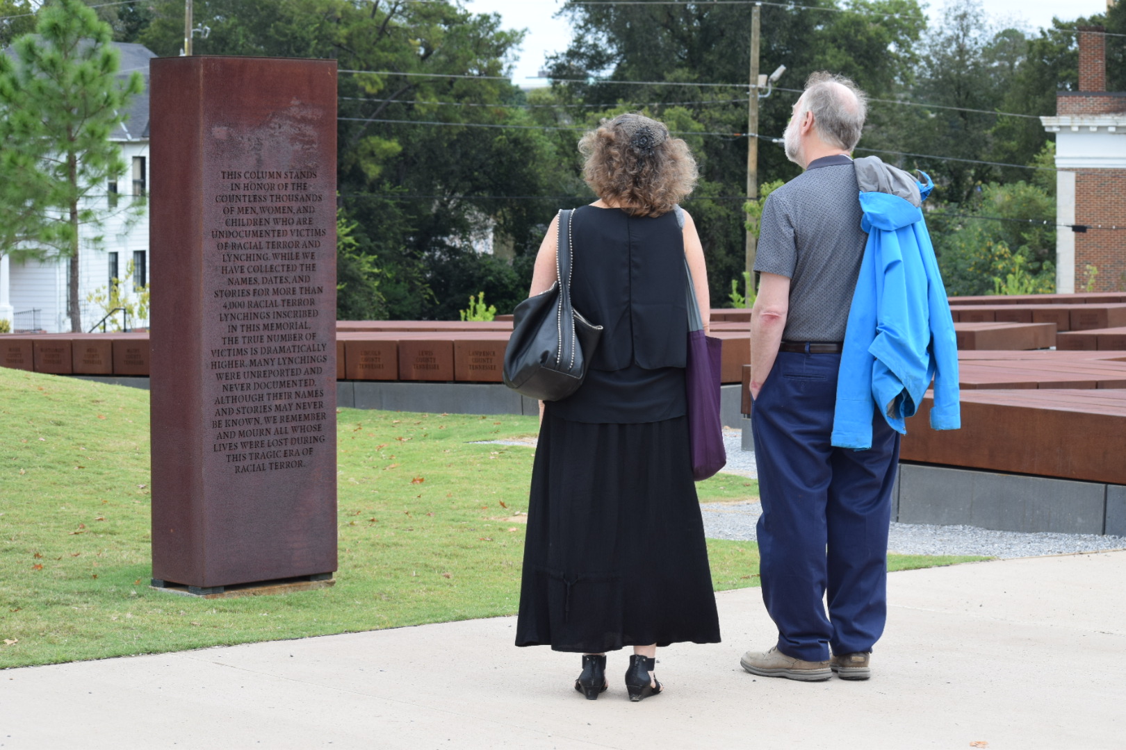 Eilberg and one other stand with their backs to us, looking at a metal plinth
