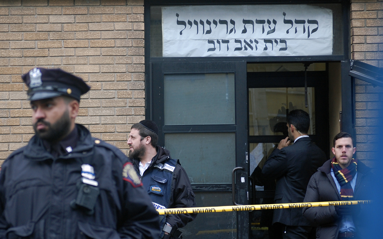 Hasidic Jews, government officials and police officers stand in front of the K'hal Adas Greenville synagogue next door to the JC Kosher Supermarket in Jersey City, N.J., the site of a deadly shooting, Dec. 11, 2019. (JTA/Laura E. Adkins)