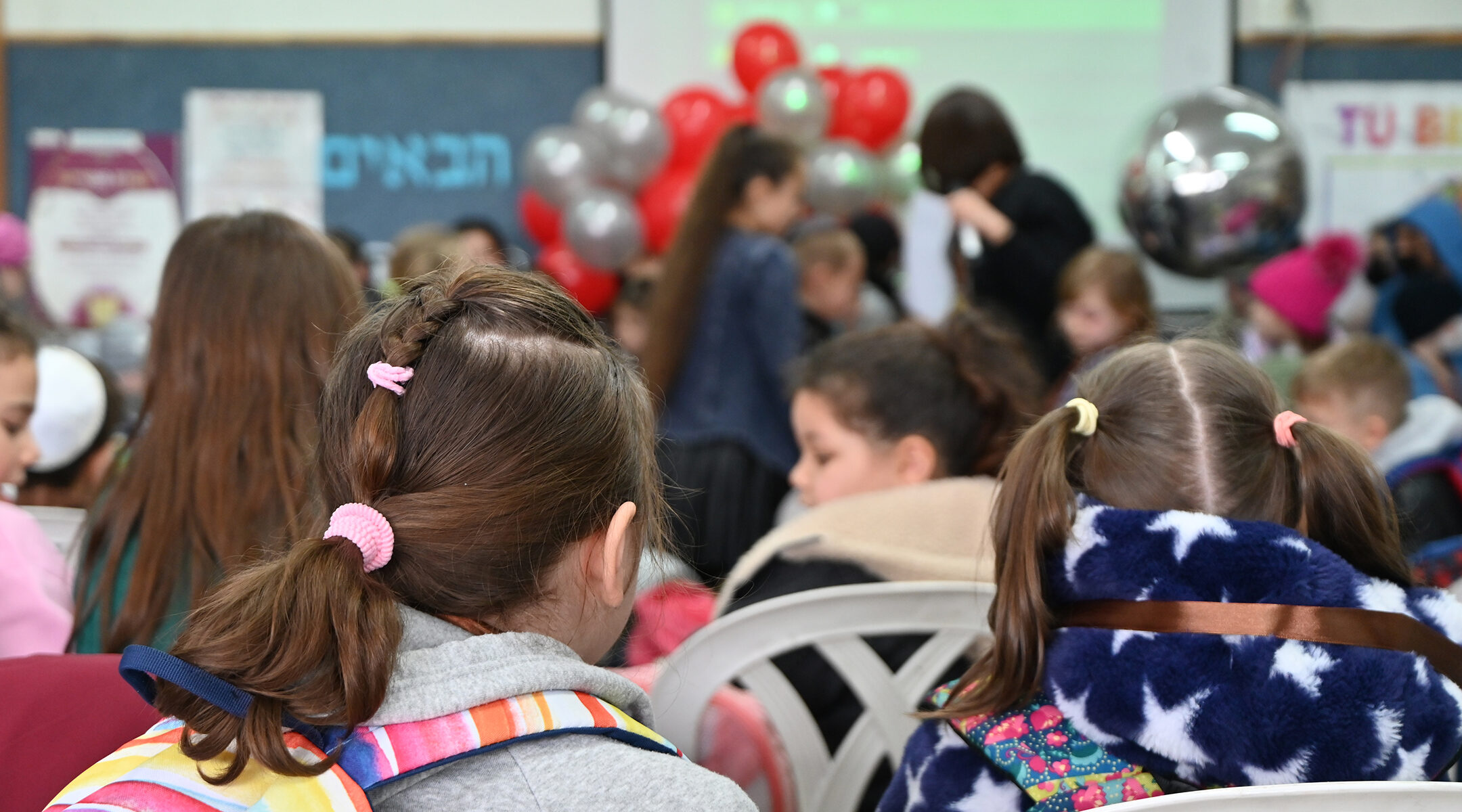 the two Ukrainian children are seen from behind among a crowd of classmates