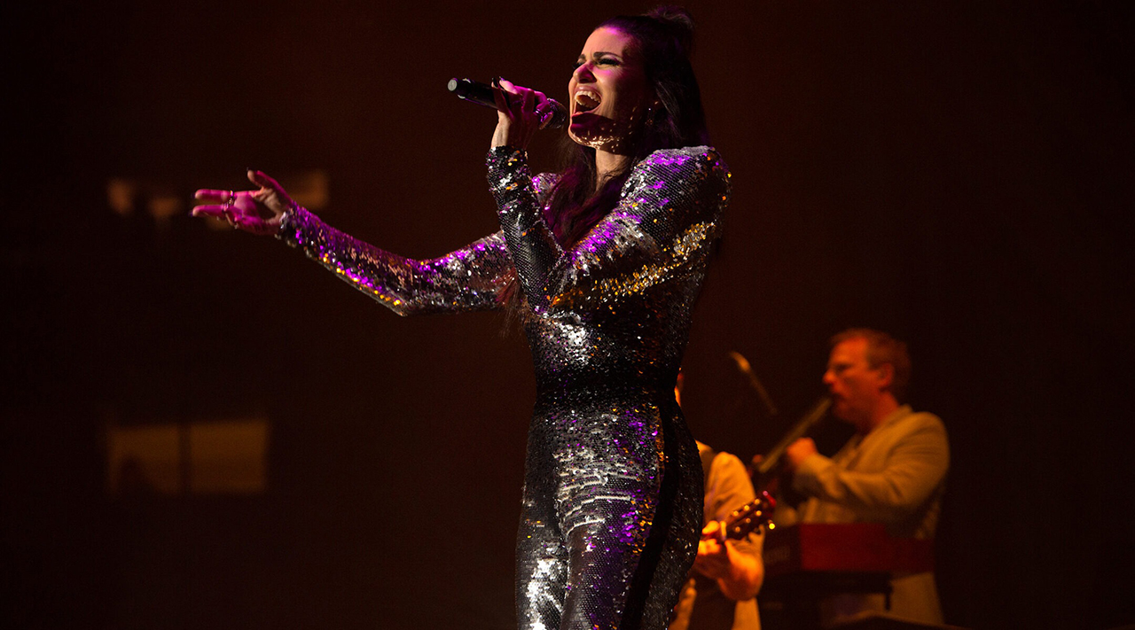 a woman in a sparkly dress sings on stage
