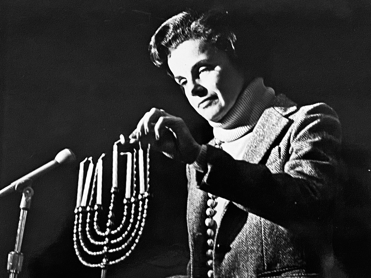 a black and white photo of Dianne Feinstein lighting a menorah
