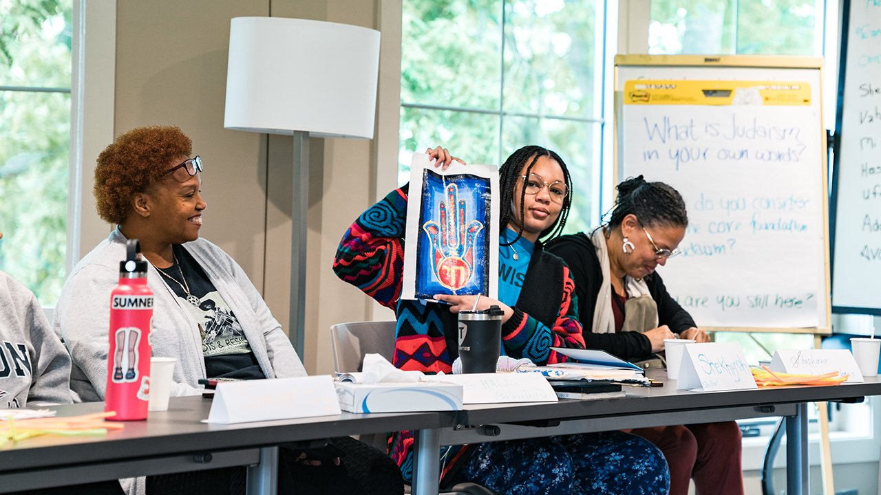 Shekhiynah Larks shows off a painting during a Jews of Color Organizing Fellowship session. (Photo/Courtesy)