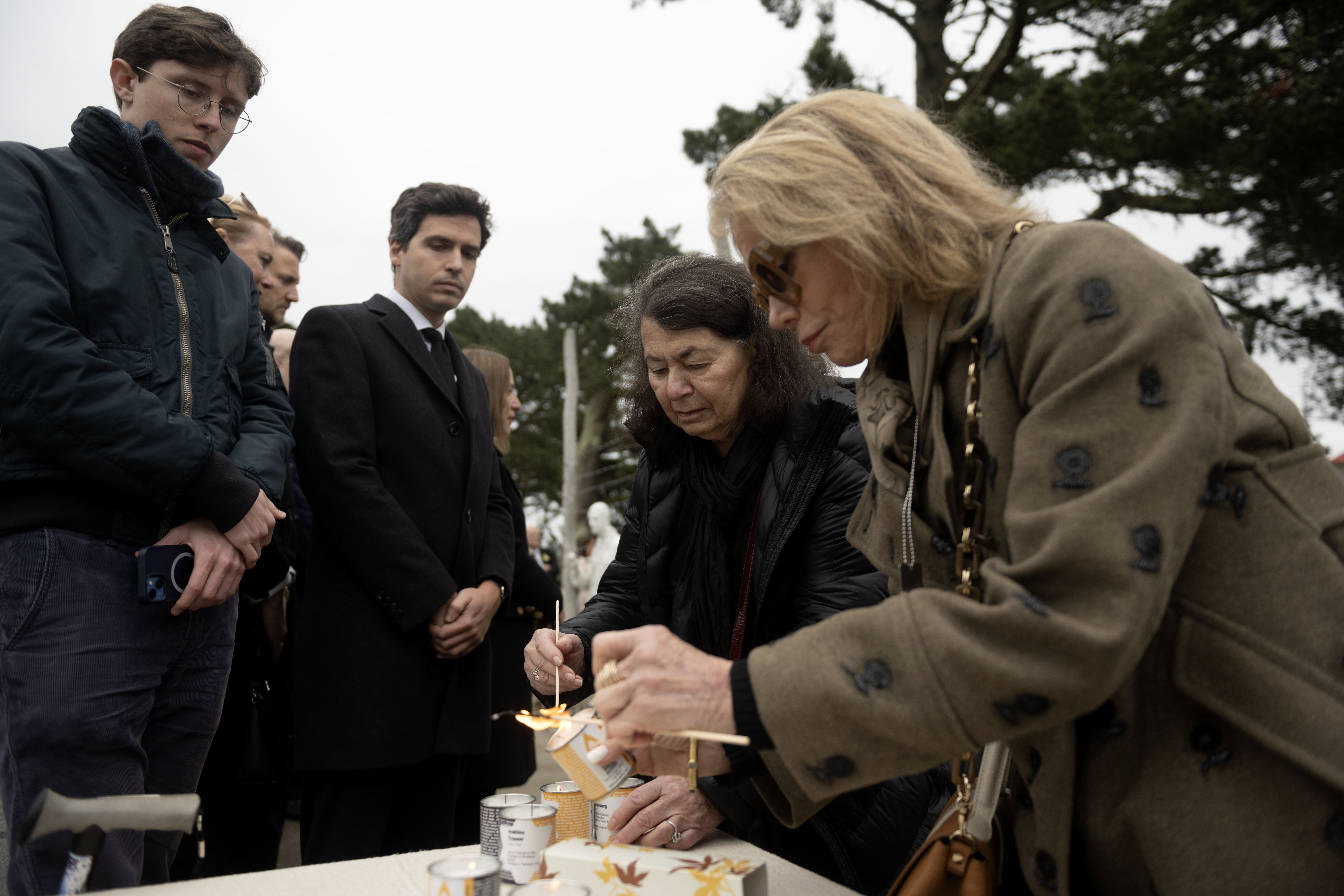 Two women light memorial candles