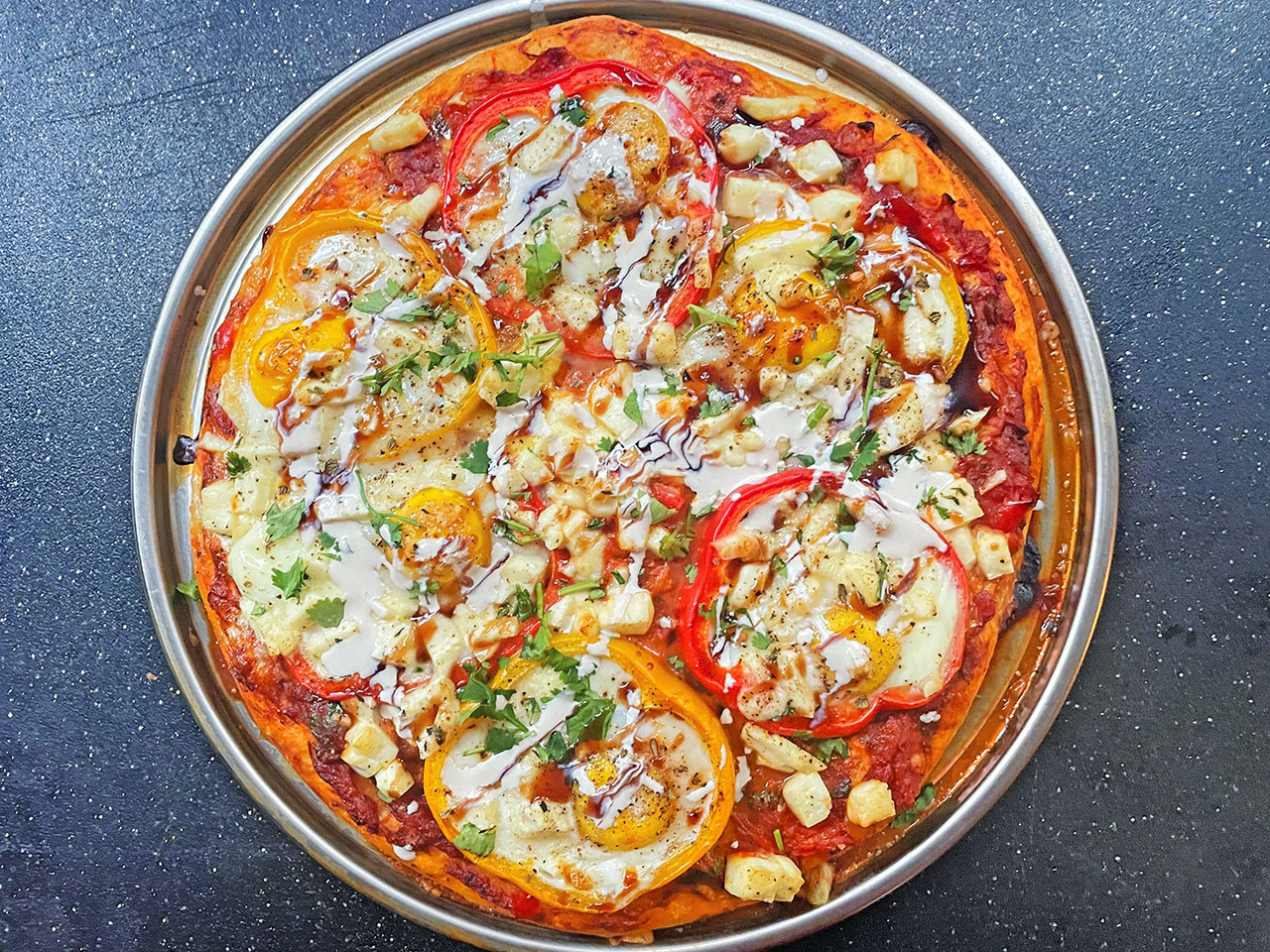 Shakshouka pizza baked and garnished with tahini sauce, silan and cilantro 
(Photo/Faith Kramer)