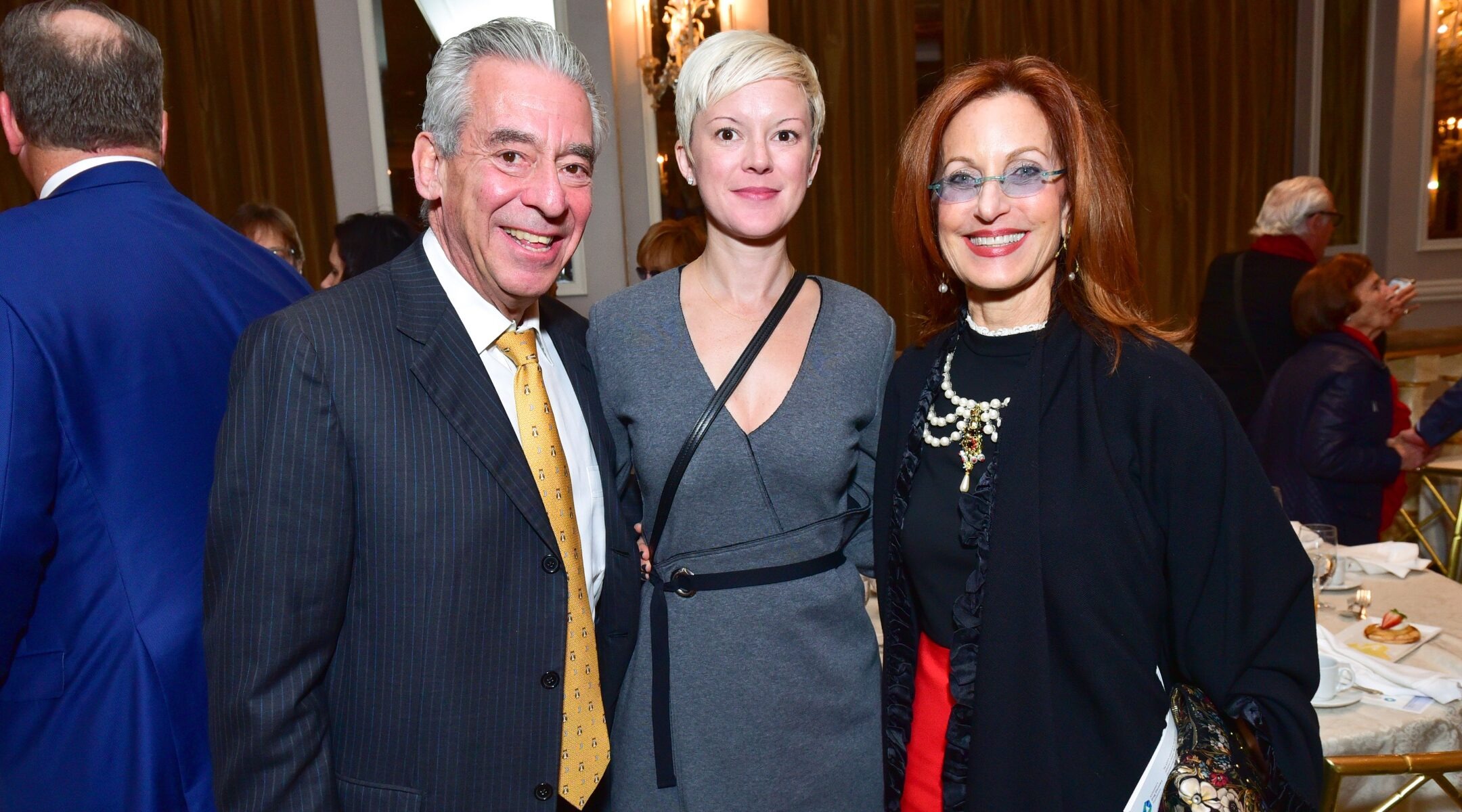 three people pose smiling at a fancy event