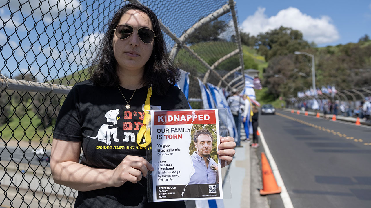 Yael Nidan Kirsht holds a poster of her brother-in-law, Yagev Buchshtab, one of the hostages held in Gaza, at a vigil commemorating six months since the Oct. 7 Hamas attack on Israel in Lafayette on Sunday, April 7, 2024. (Photo/Aaron Levy-Wolins)