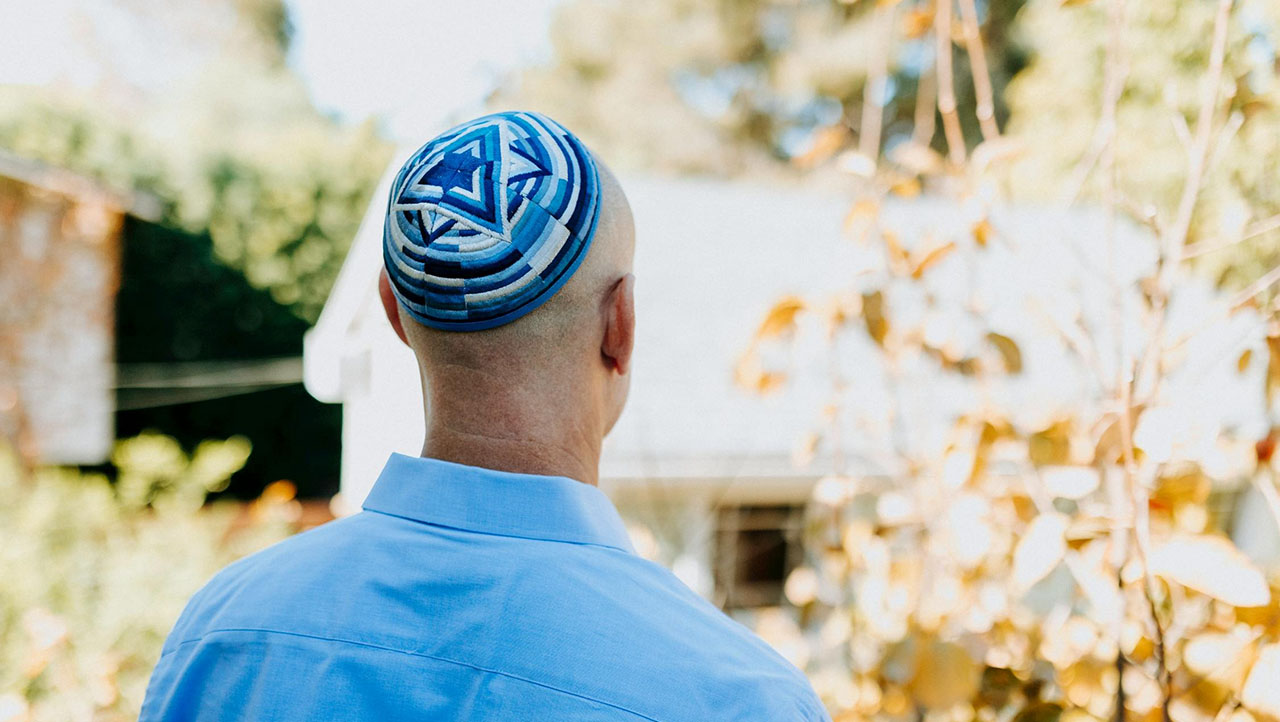 a man wearing a yarmulke, seen from behind