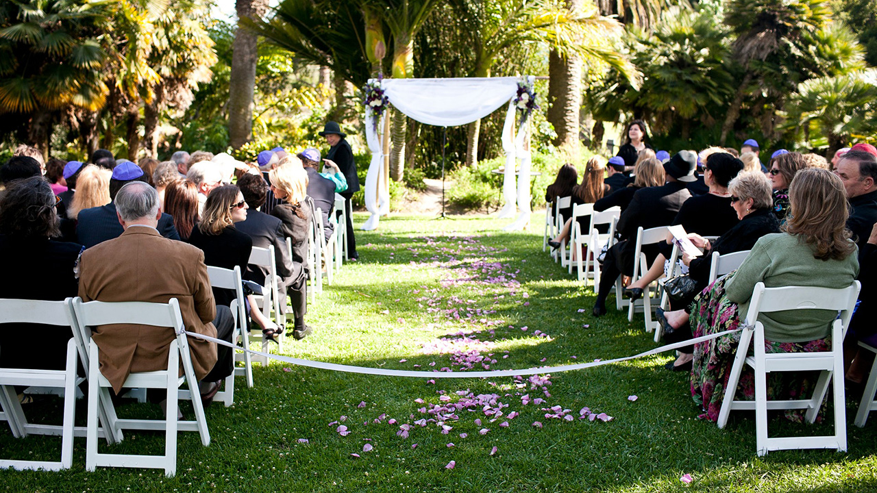 rows of seated guests seen from behind, with a chuppah at the far end