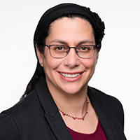 a smiling middle aged white woman with glasses and dark hair