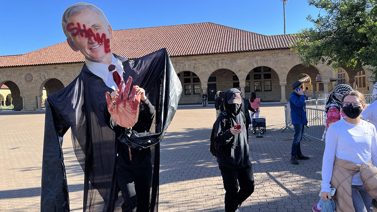 A protester carries a large cutout image of Richard Saller, Stanford's interim president, with "Shame" written across his face on June 5, 2024. (Photo/Andrew Esensten)