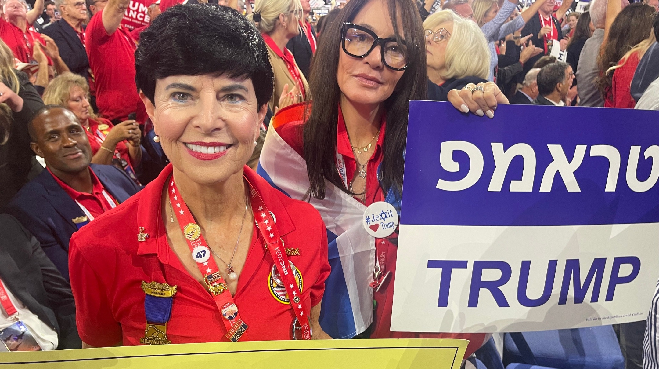 Linda Stoch, left, and Michelle Terris, right, hold up Jews for Trump signs at the Republican National Convention, Milwaukee, July 16, 2024. (Ron Kampeas/JTA)