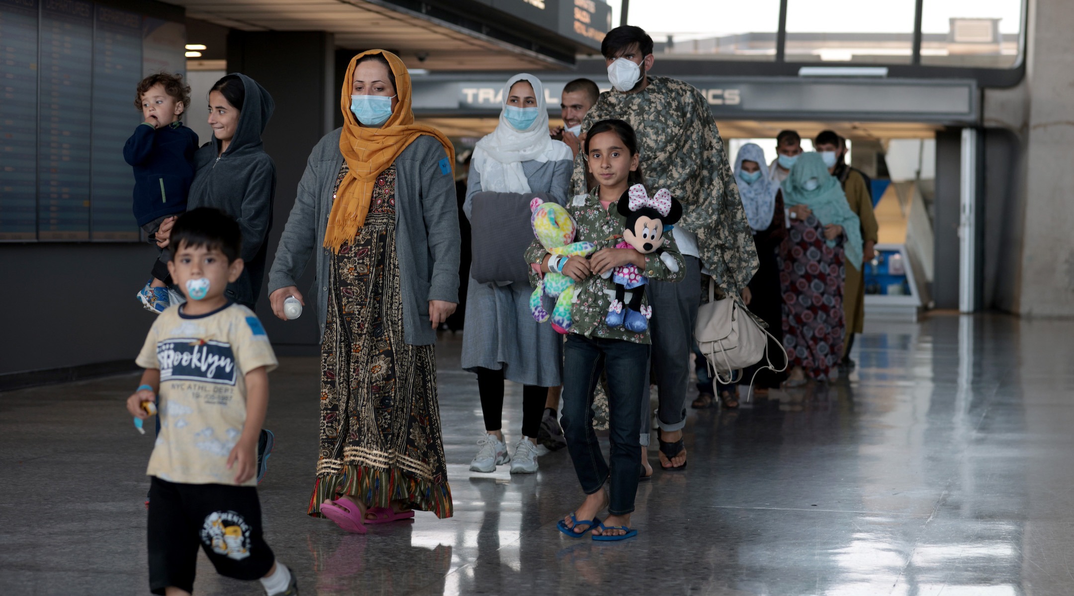 A family evacuated from Afghanistan is led through the arrival terminal at Dulles International Airport in the Washington area to board a bus that will take them to a refugee processing center, Aug. 25, 2021.  (Anna Moneymaker/Getty Images)