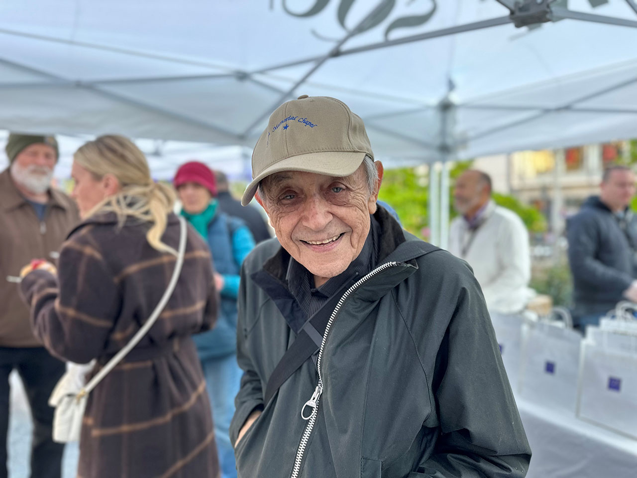 Emil Knopf with a Sinai Memorial Chapel hat on at Sinai's Hanukkah outreach booth in San Francisco's Union Square, 2022. Sinai was one of many Jewish organizations Knopf donated his time to over the years. (Courtesy)