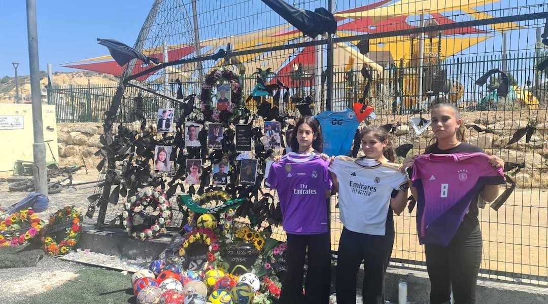 Three young girls stand in front of a memorial display near the site of the attack