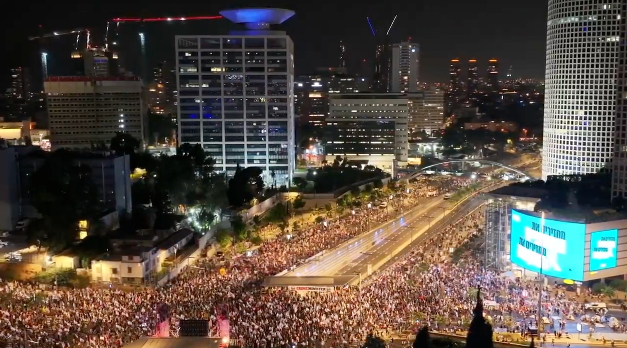overhead shot of thousands of people marching through a street at night