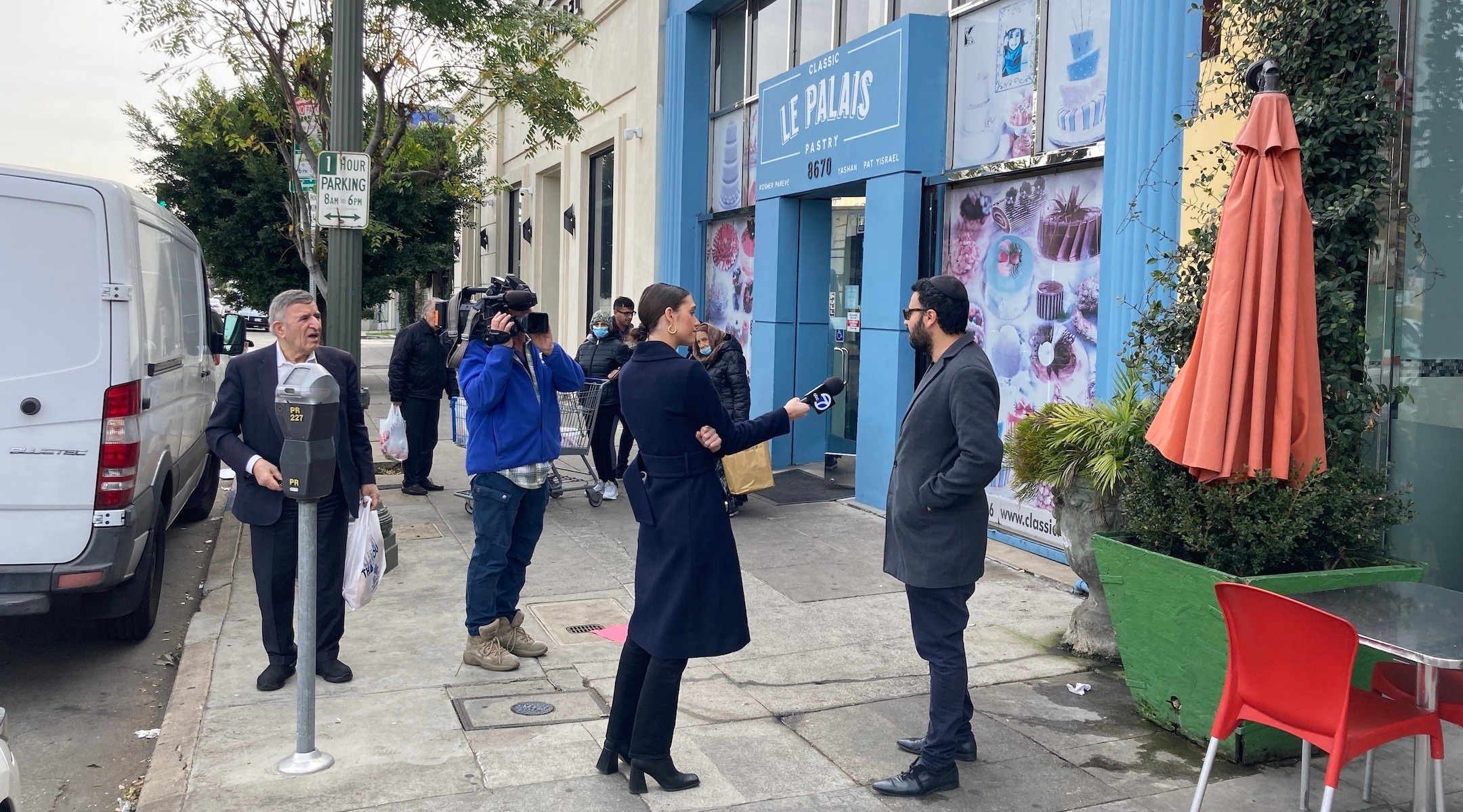 A woman with a microphone speaks to a man with a kippah on his head