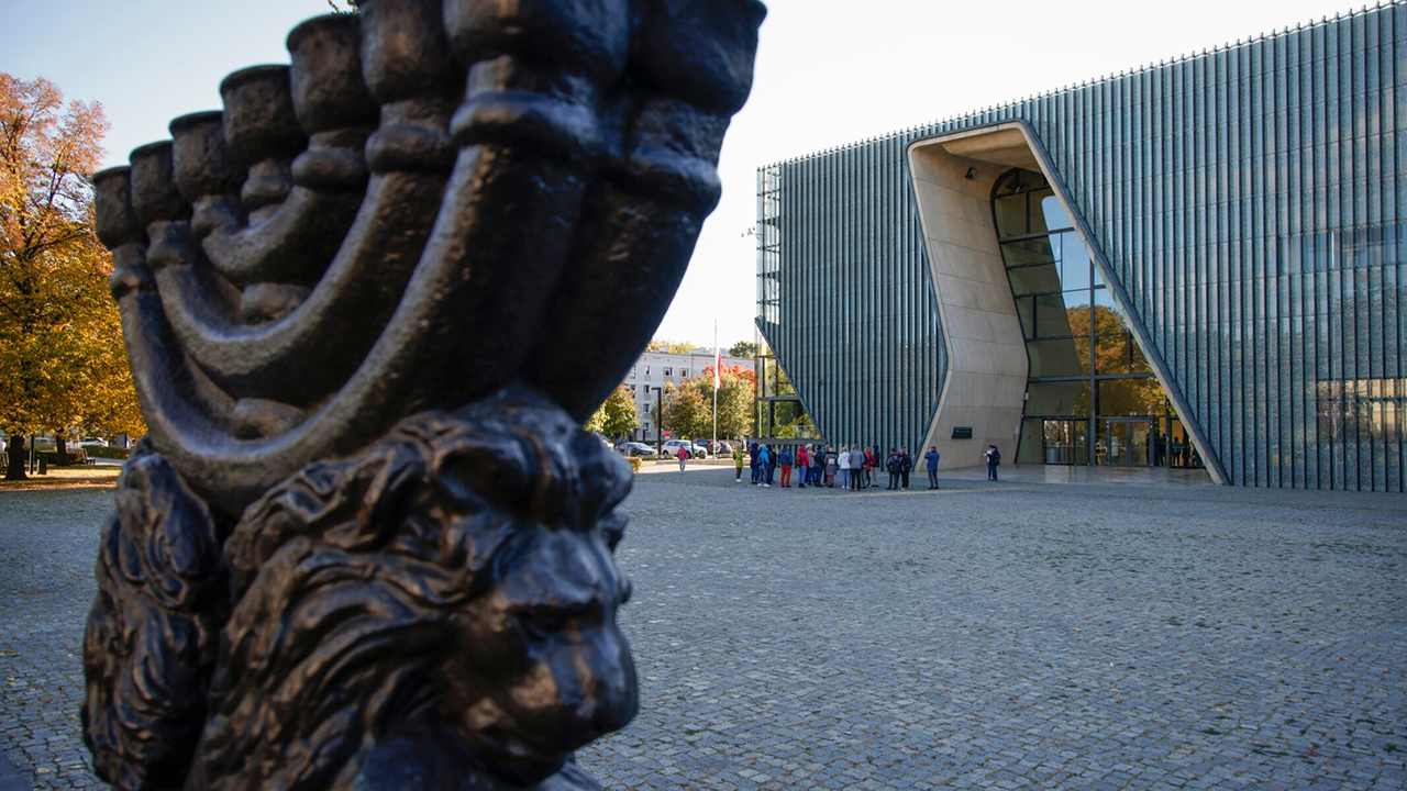a statue of a menorah in front of a stark modernist building