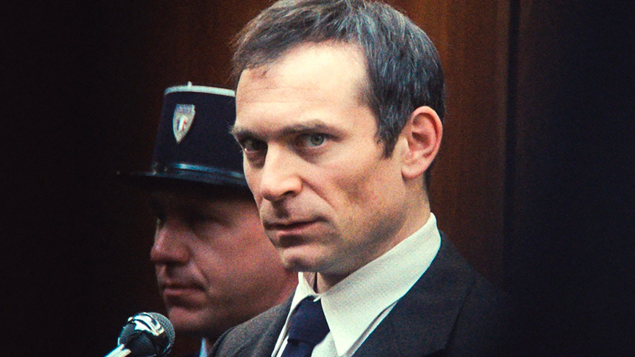 a man in a suit in front of a microphone in a courtroom