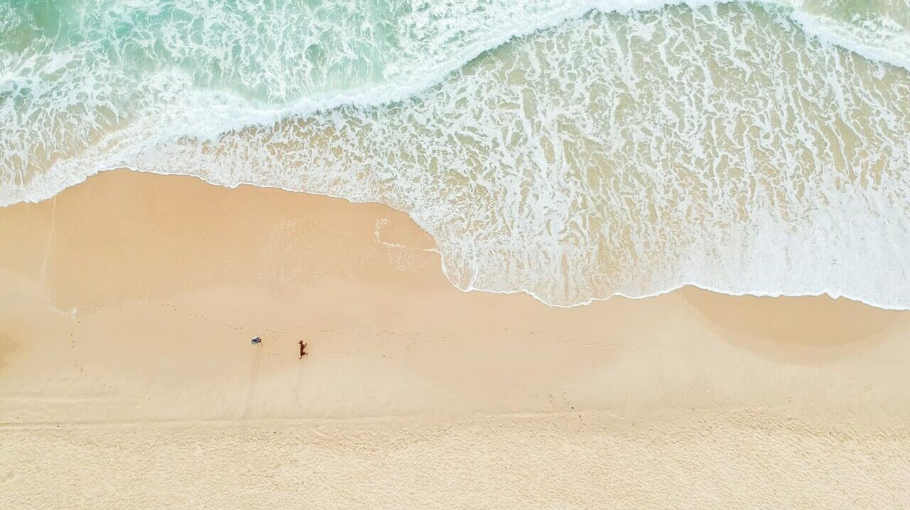 waves crash on a beach, seen from above