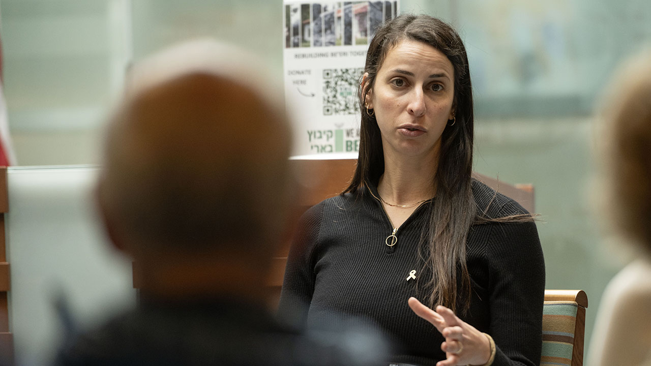 A woman speaks to a small audience in a synagogue sanctuary