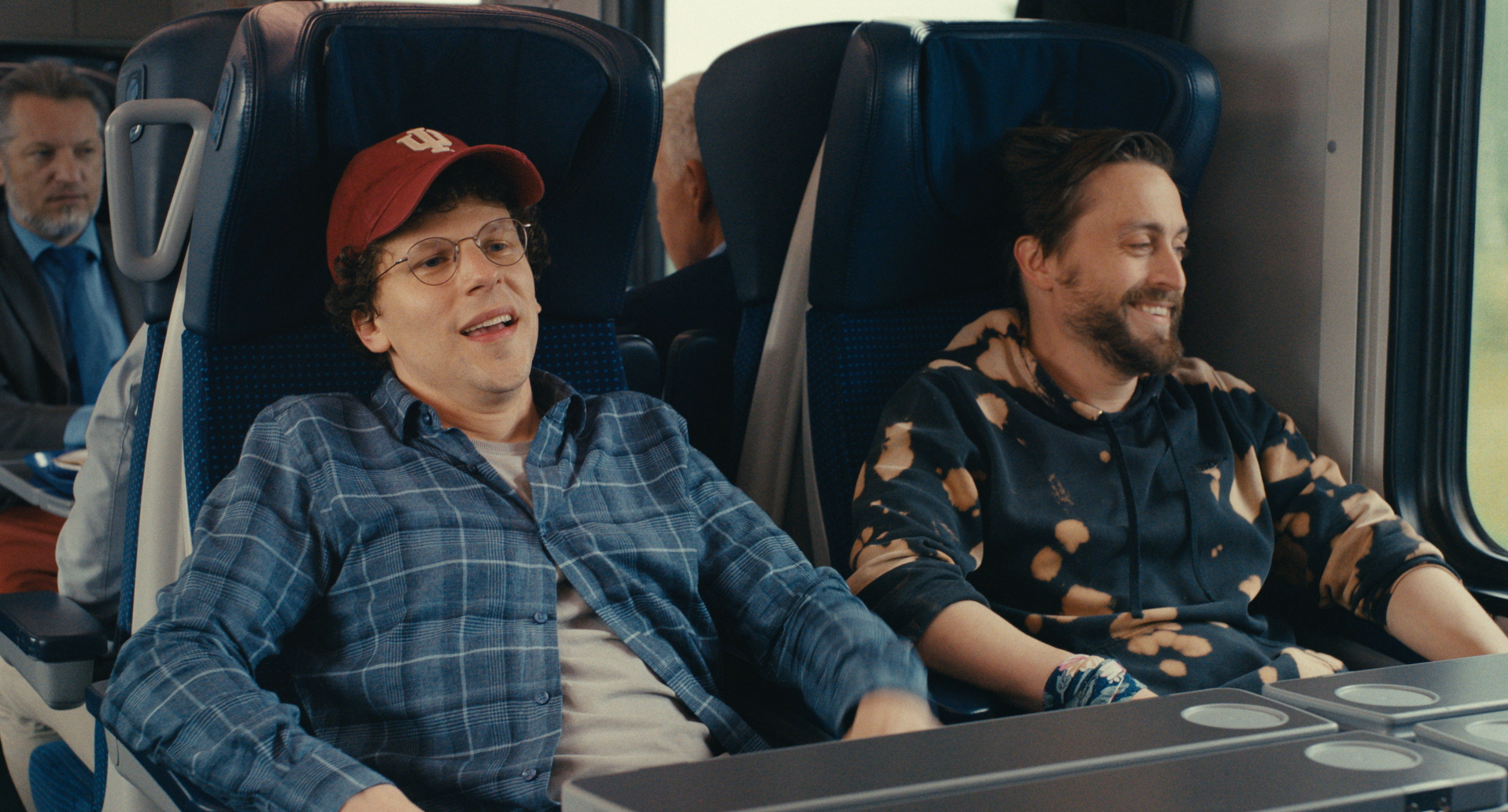 two younger men sit on a train