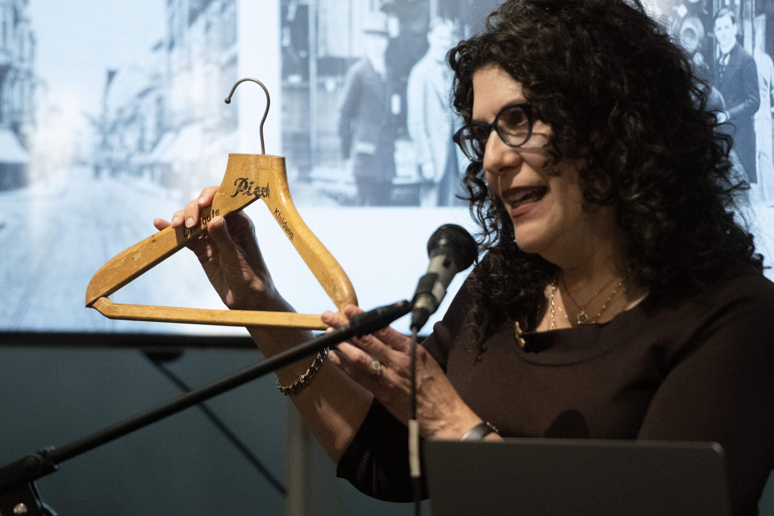 a woman holds up an old wooden coathanger