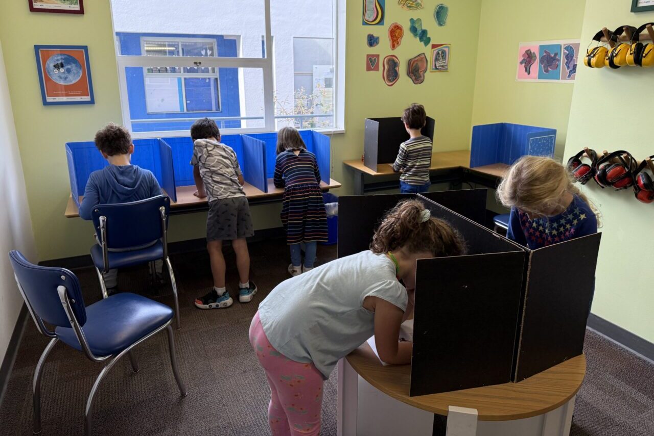First-graders cast their ballots at a "polling place" in Brandeis School's main office. (Lea Loeb/J. Staff)